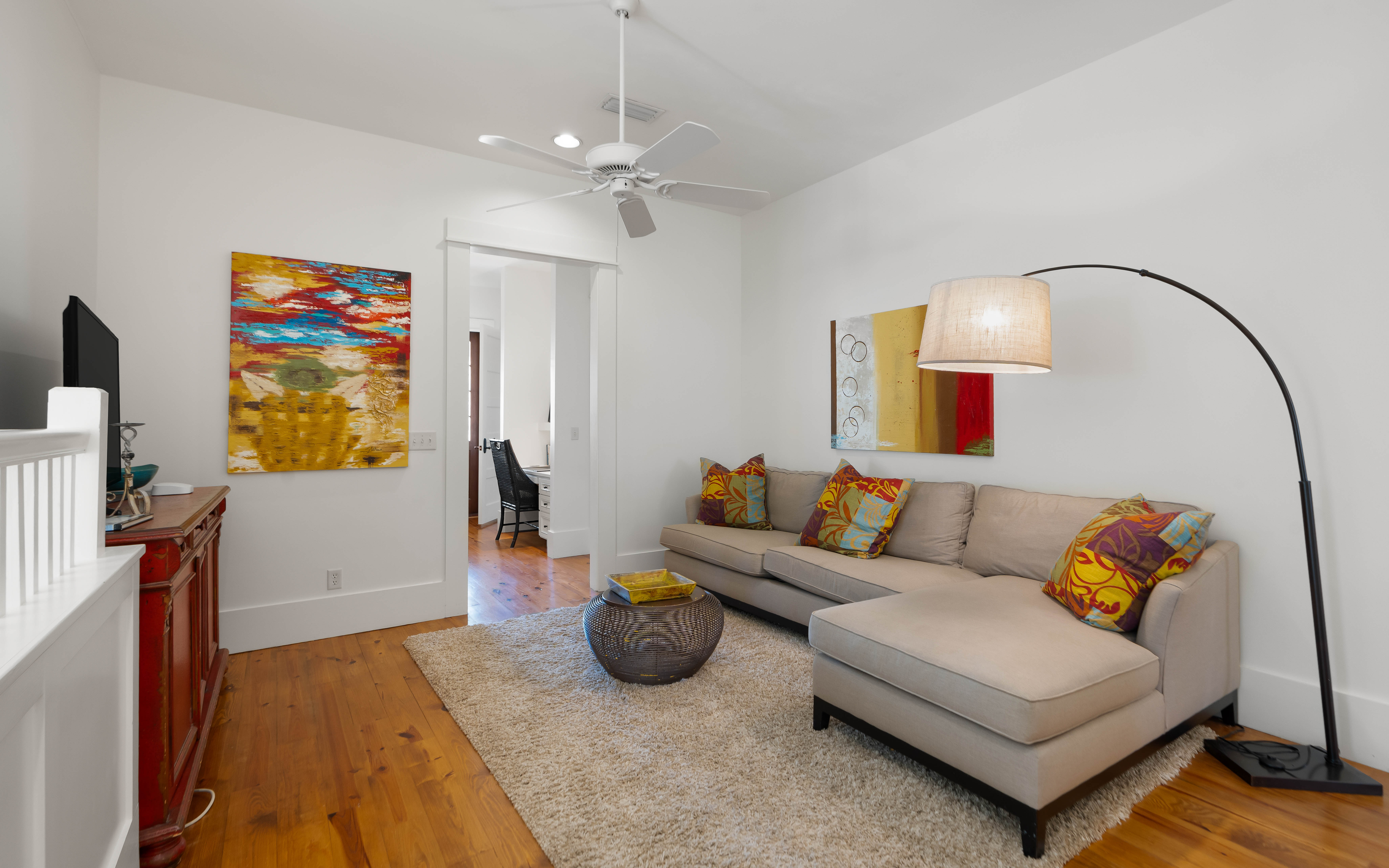 Relax in your stylish living room with vibrant art, plush sectional seating, and warm wood floors that create the perfect atmosphere.