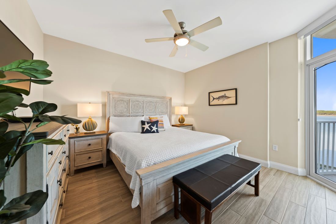 Unwind in your serene bedroom with coastal charm, featuring a plush bed and private balcony access for fresh morning air.