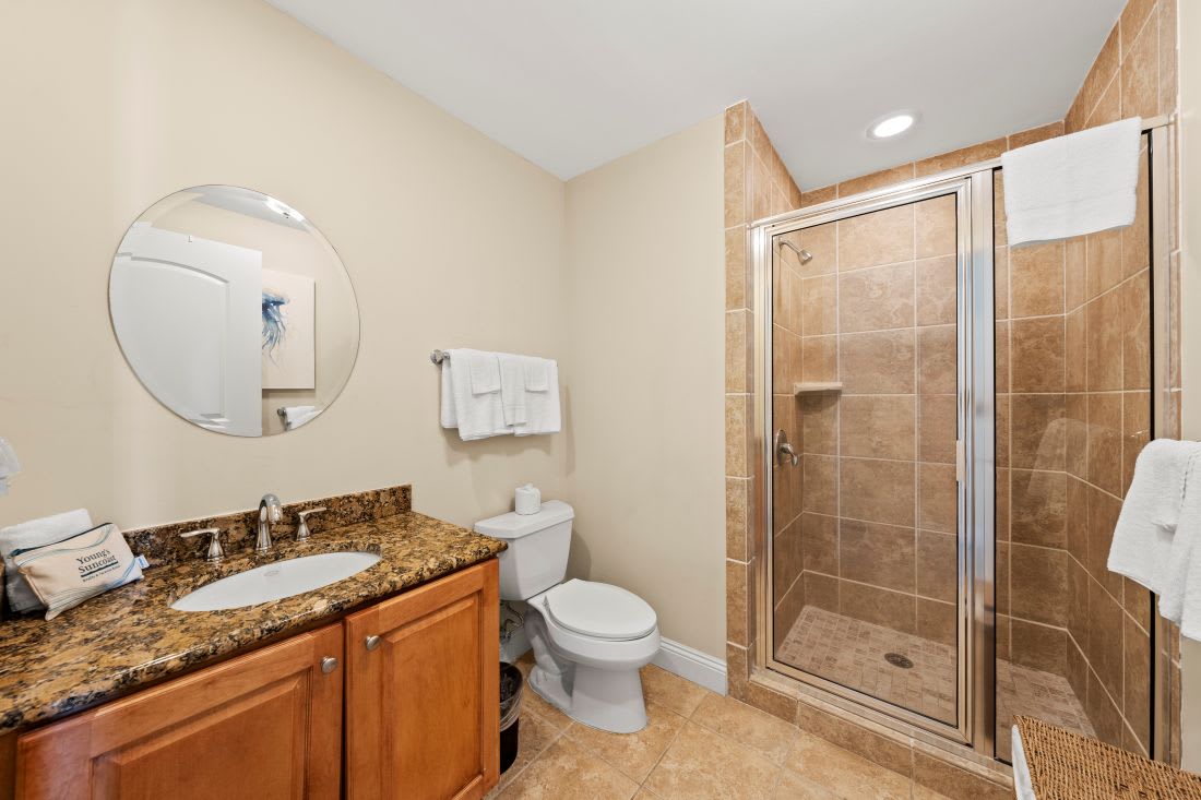 Refresh in your elegant bathroom featuring a spacious glass shower, granite counters, and warm tile finishes.