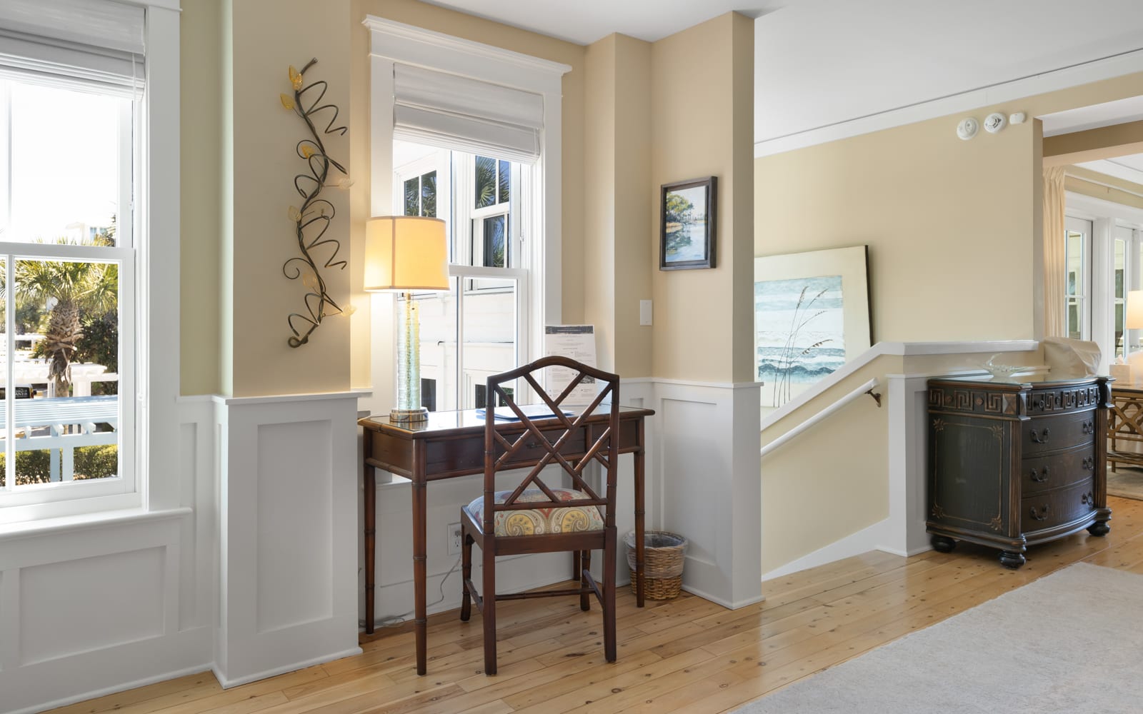 Settle into your charming writing nook with coastal artwork and warm natural light streaming through windows.