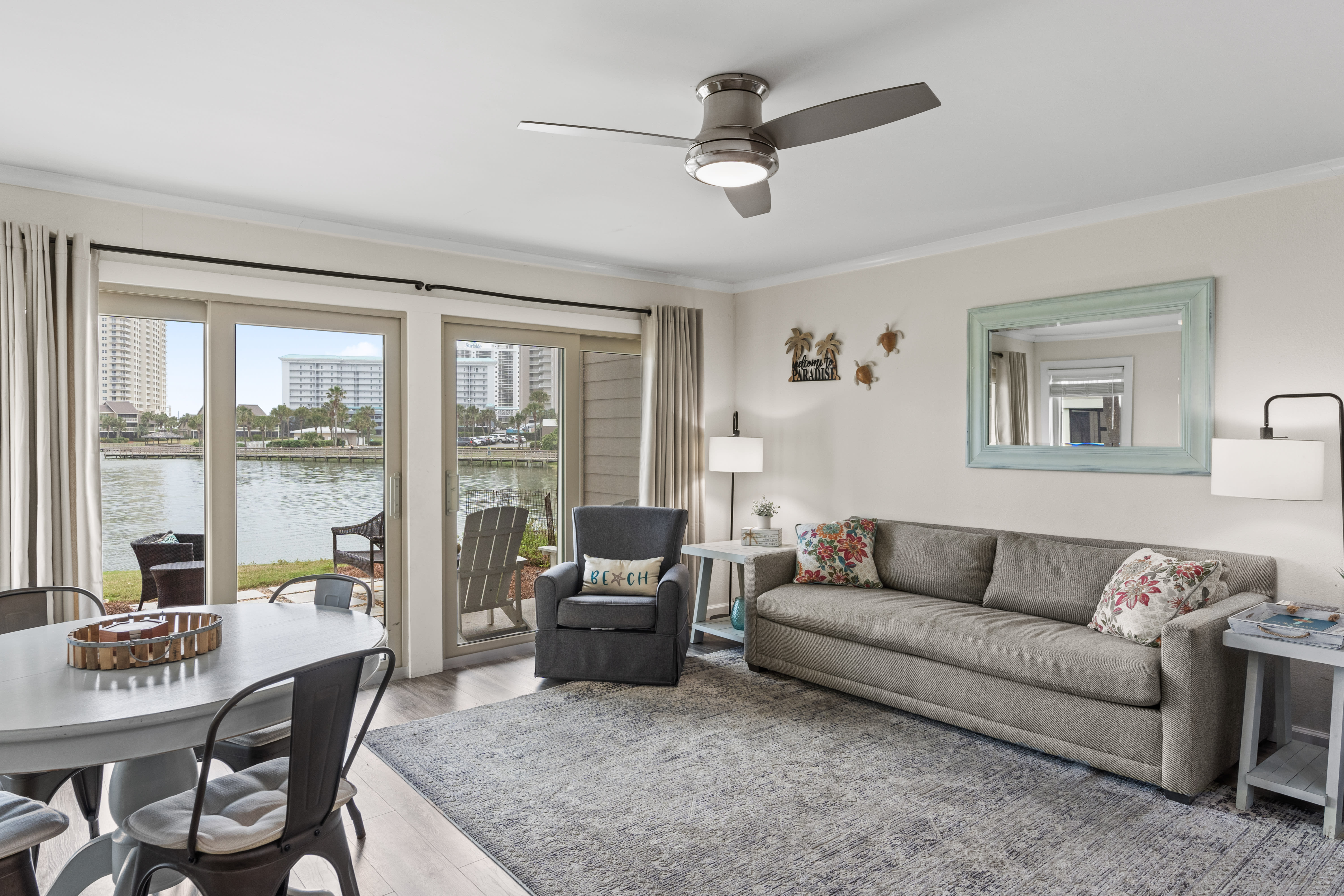 Relax in your waterfront living room with panoramic windows framing stunning lake views and comfortable seating for peaceful evenings.