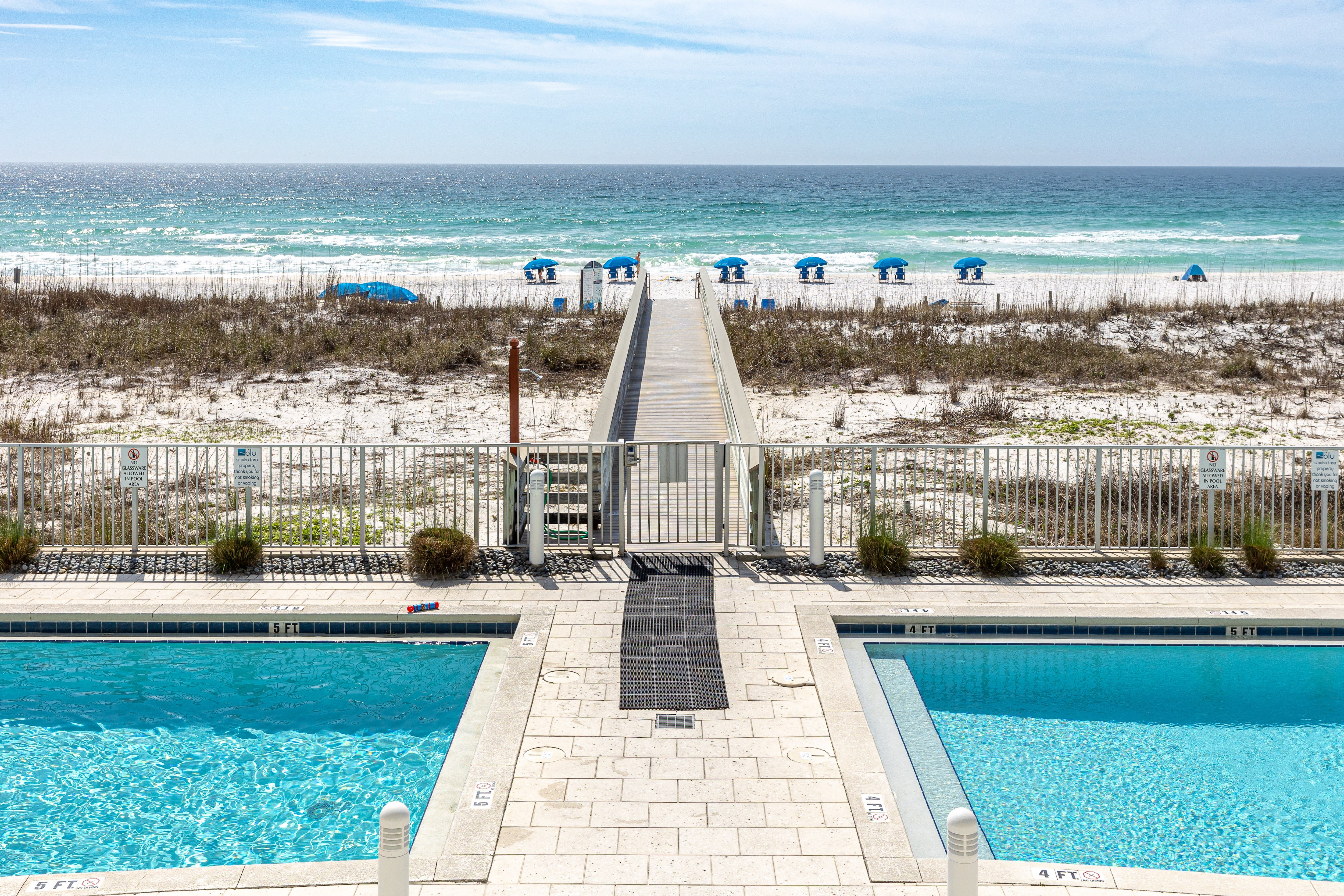 Pristine beachfront resort with swimming pool, boardwalk access to white sand beach and emerald waters.