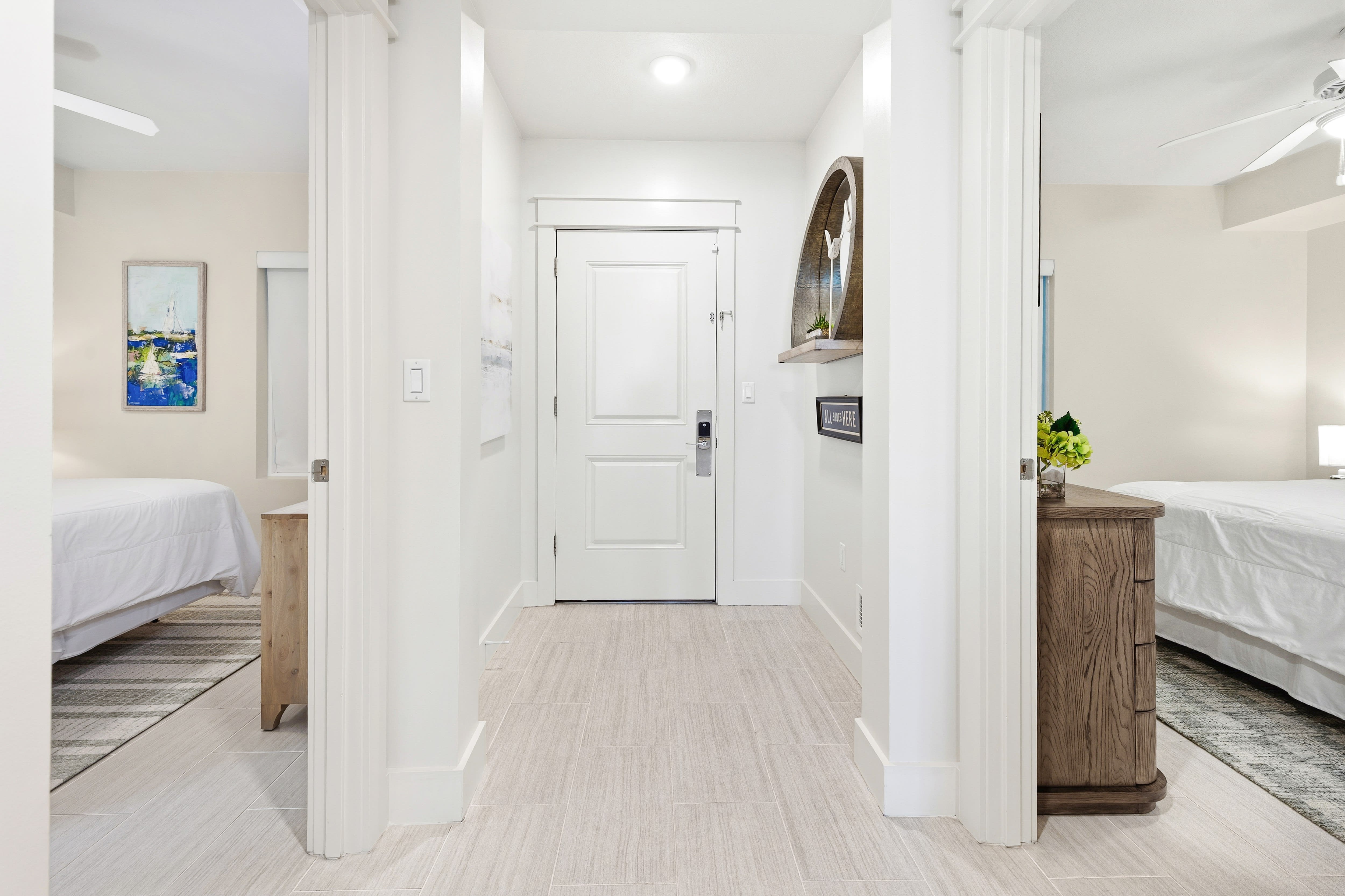 Step into your bright, modern hallway connecting two comfortable bedrooms with clean white walls and warm wood finishes throughout.