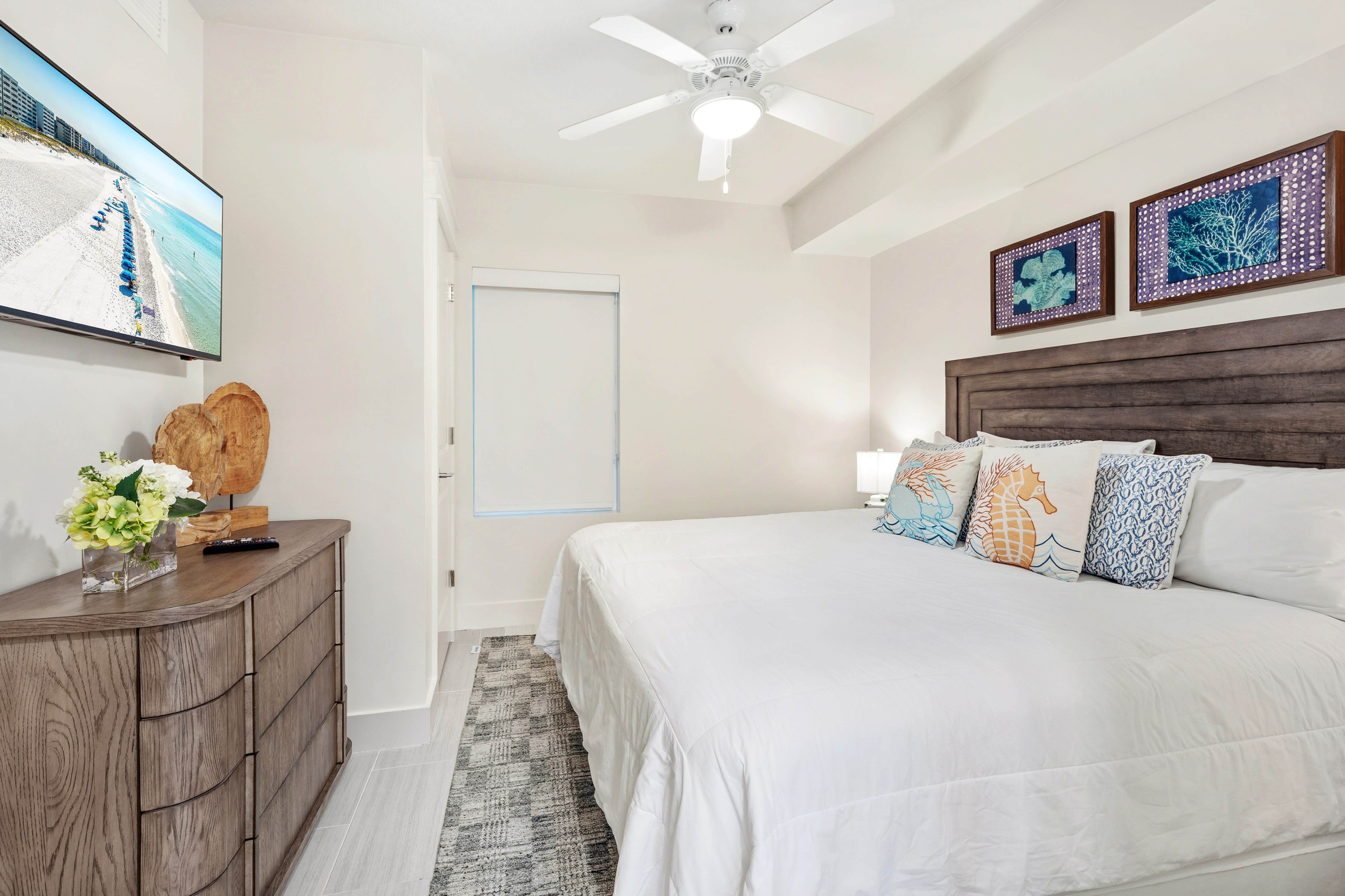 Sink into crisp white linens and coastal-themed pillows in your serene bedroom, where gentle ceiling fan breezes keep you cool.