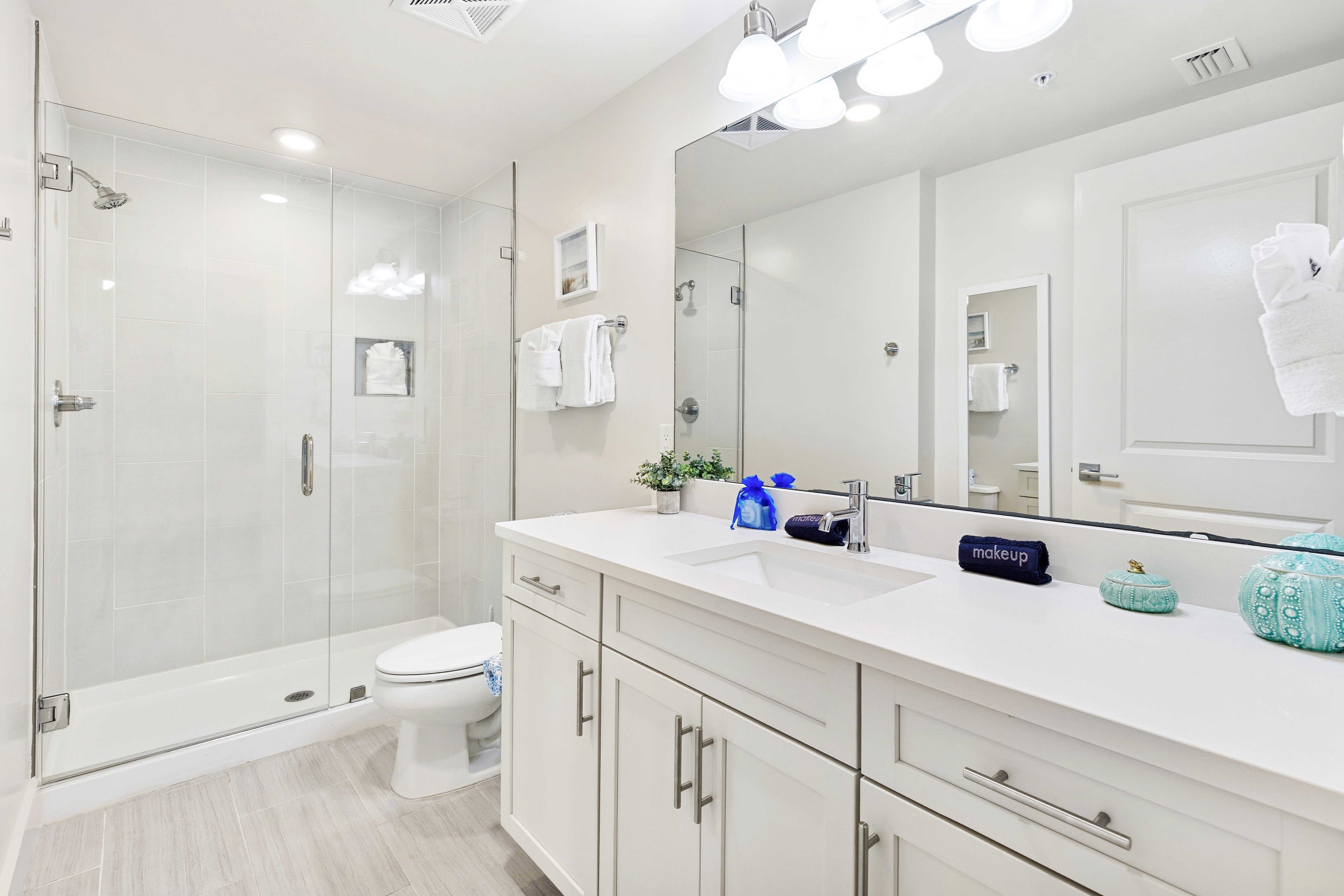 Refresh in your spacious modern bathroom with a glass-enclosed shower, dual vanities, and pristine white finishes that create a spa-like retreat.