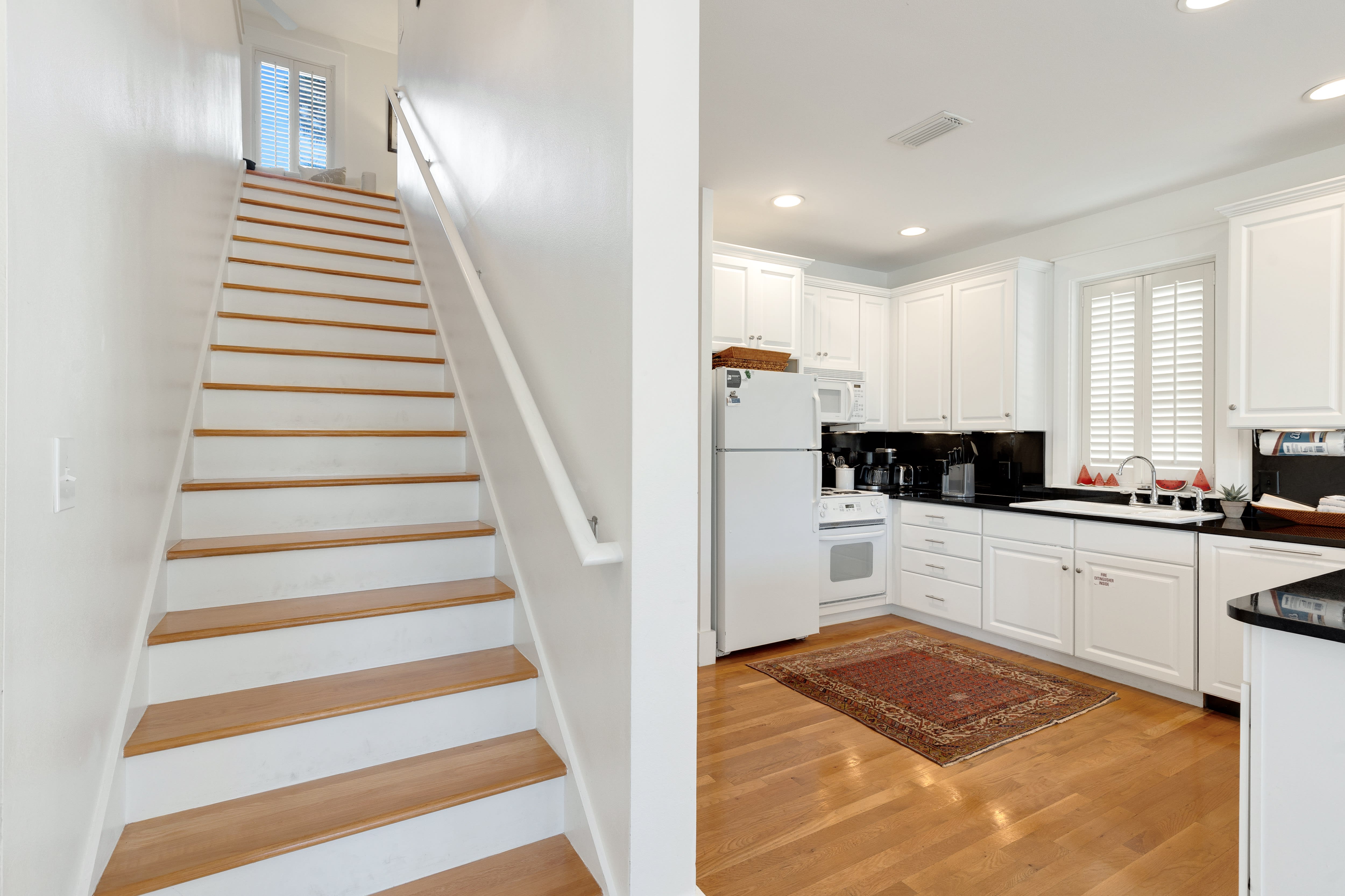 Your bright, modern kitchen flows seamlessly with elegant wooden stairs, creating a welcoming space for cooking and gathering.