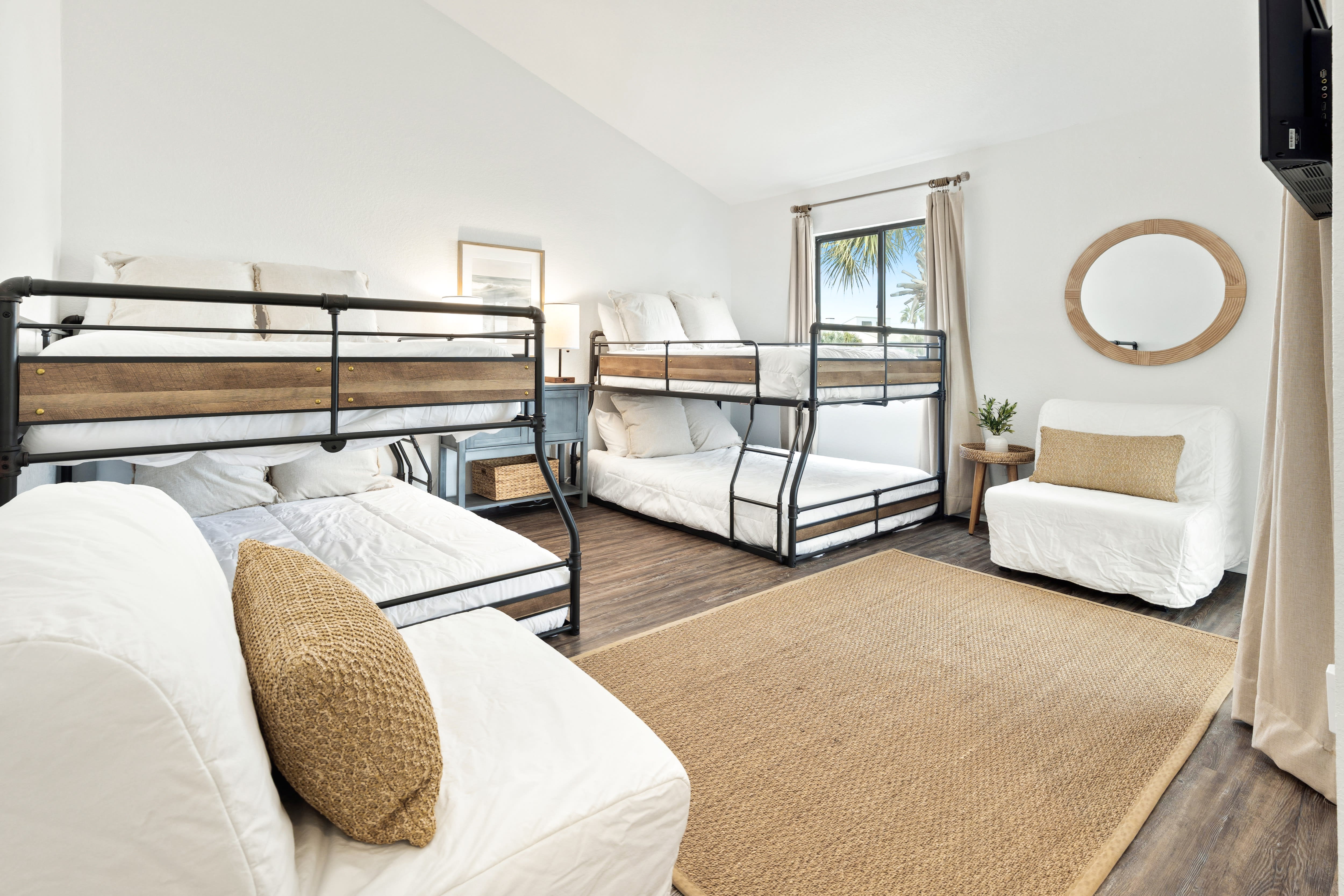 Your spacious bedroom features multiple bunk beds with crisp white linens and natural textures, perfect for families or groups.