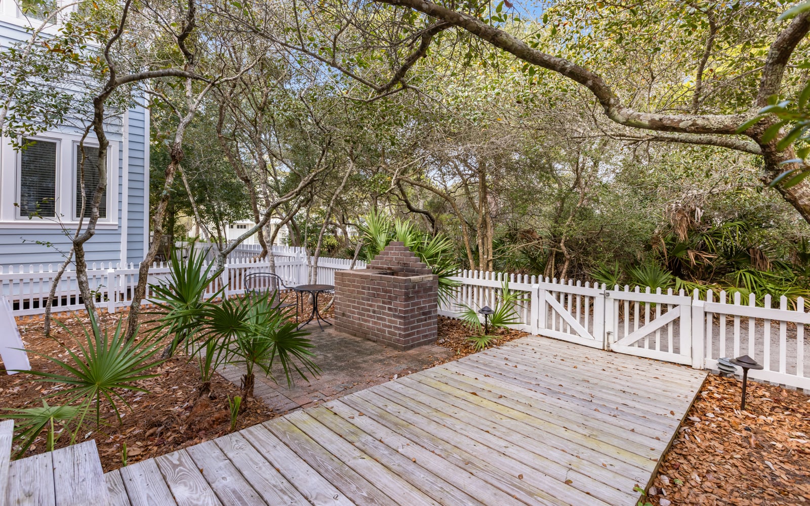 Relax on your private deck surrounded by lush coastal trees and tropical palms, with a charming brick fireplace for cozy evenings.