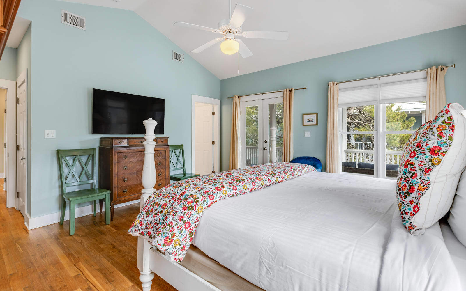 Drift off in your serene bedroom sanctuary with soothing mint walls, charming floral accents, and French doors opening to outdoor views.