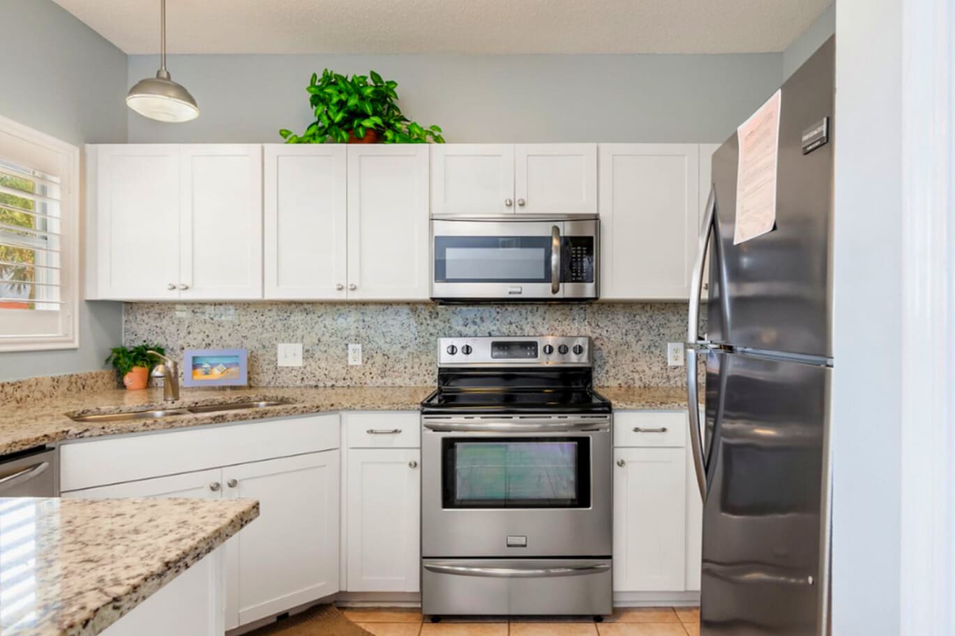 Modern coastal kitchen featuring stainless steel appliances, granite countertops, crisp white cabinetry, and a functional layout designed for easy meal prep and relaxed coastal living.