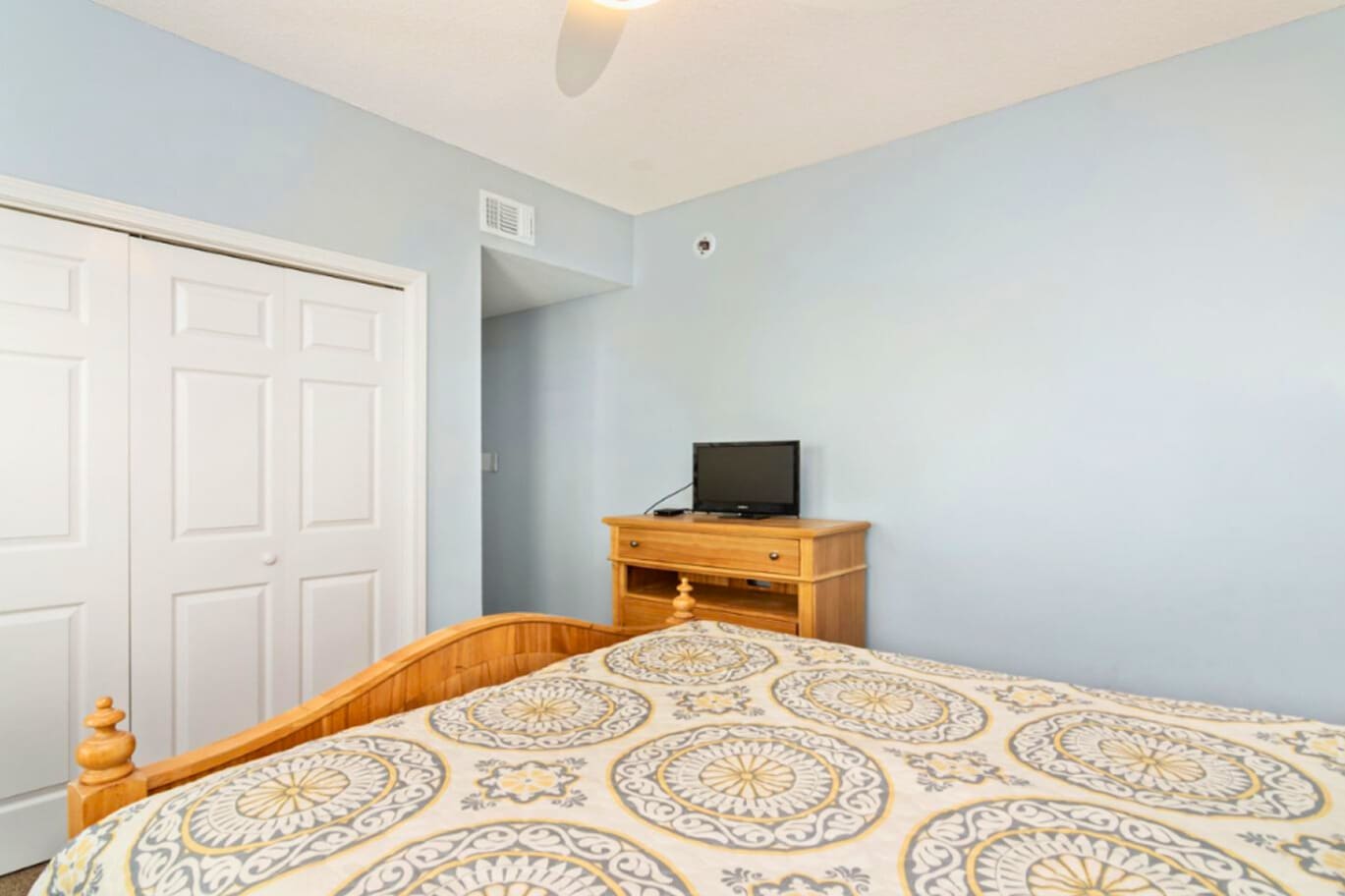 Rest easy in your comfortable bedroom with soft blue walls and warm wood accents creating a peaceful retreat.