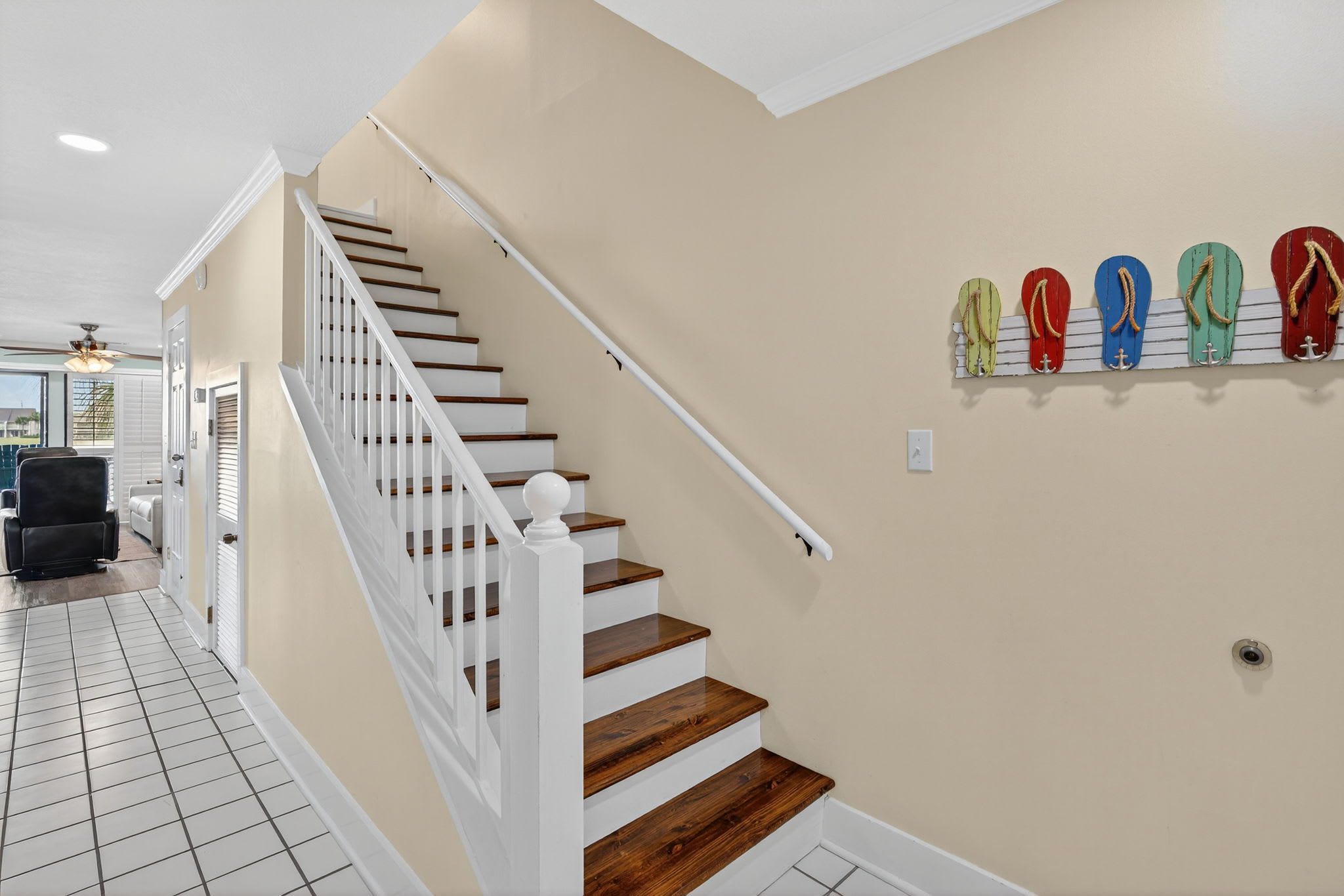 Welcoming interior staircase with coastal charm - colorful flip-flops displayed on the wall add a playful beach house touch to your stay.