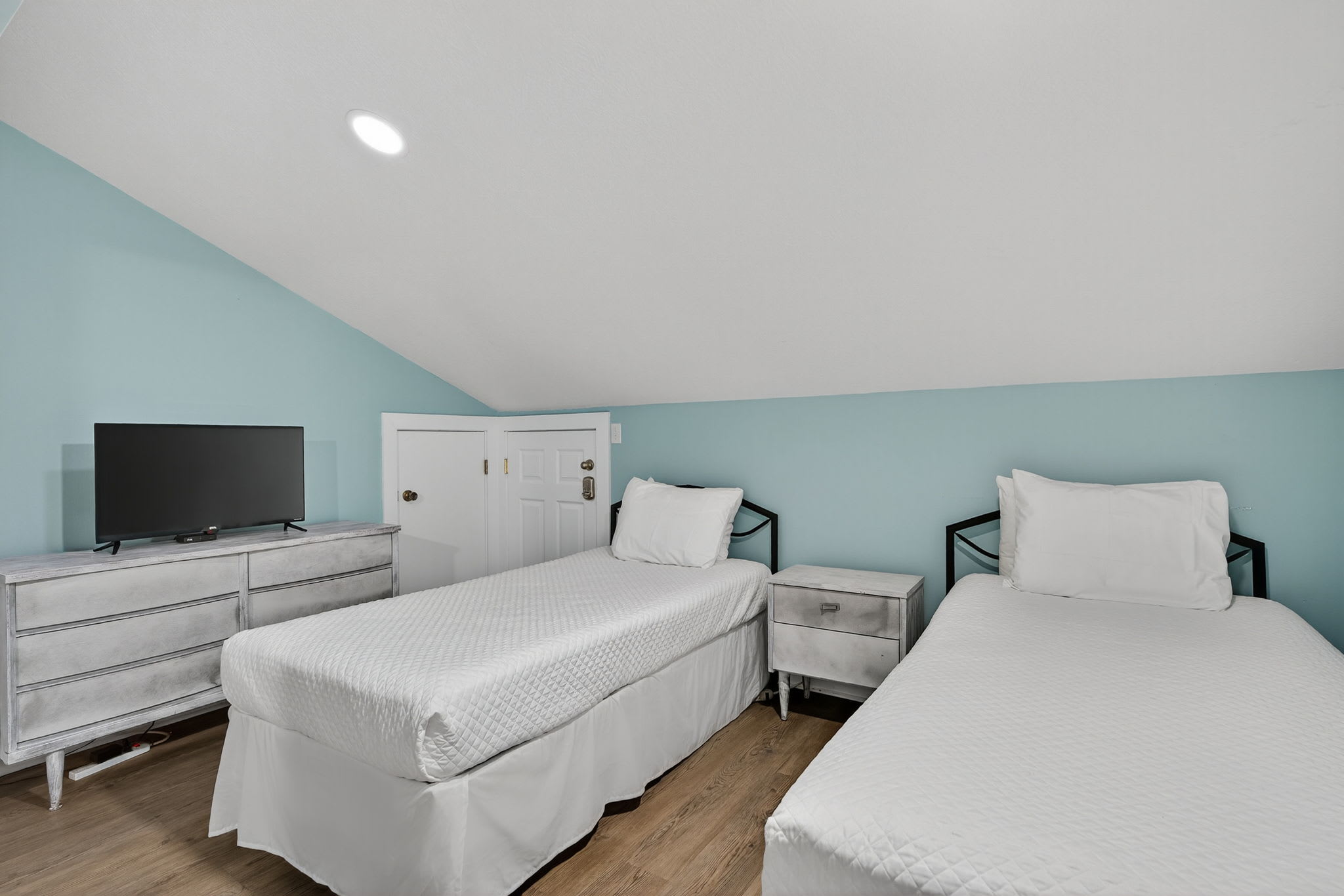 Your peaceful twin bedroom features comfortable beds with crisp white linens, modern furnishings, and a flat-screen TV for your entertainment.