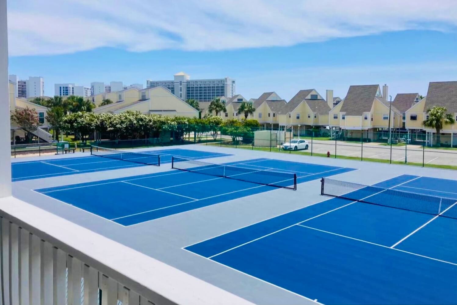 Lighted tennis courts at Sandpiper Cove Resort, offering a pristine setting for casual matches or competitive play, surrounded by lush landscaping and a relaxed coastal resort atmosphere.