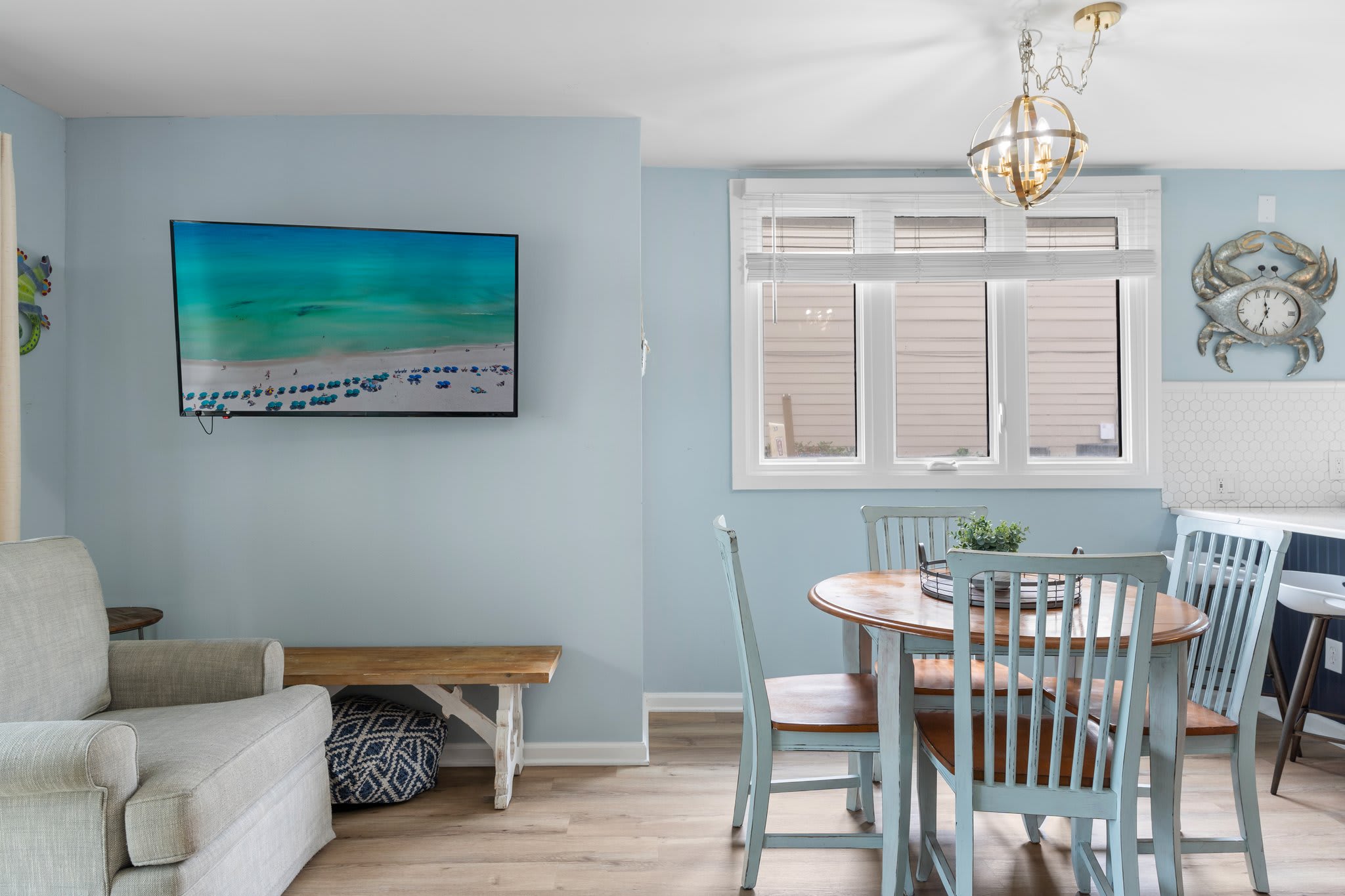 Cozy dining nook with a round wooden table, seafoam chairs, and a widescreen TV —perfect for casual meals or family game nights.