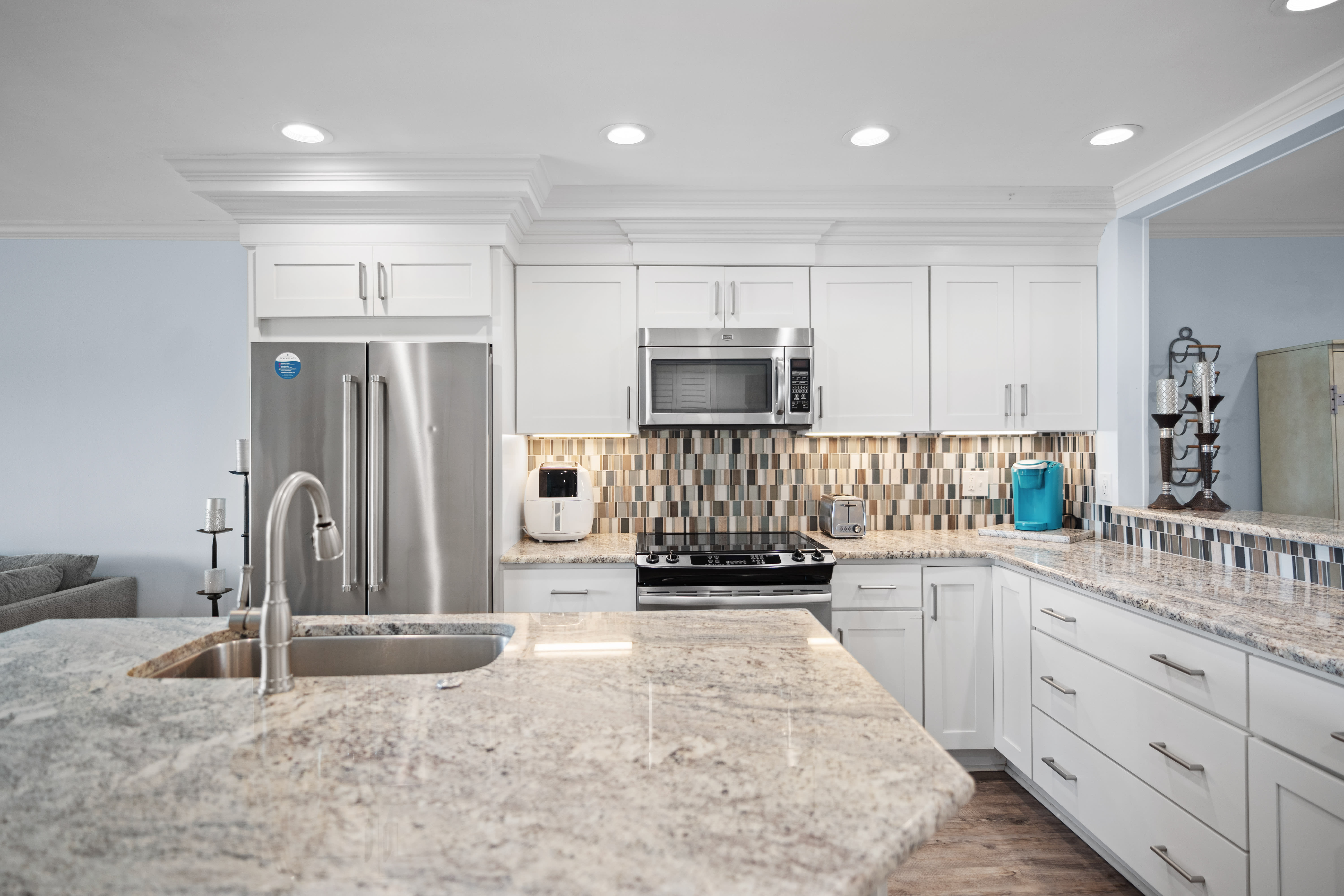 Sleek kitchen with granite countertops, stainless steel appliances, white cabinetry, and a bold tile backsplash. Bright, modern, and fully equipped for cooking and entertaining.