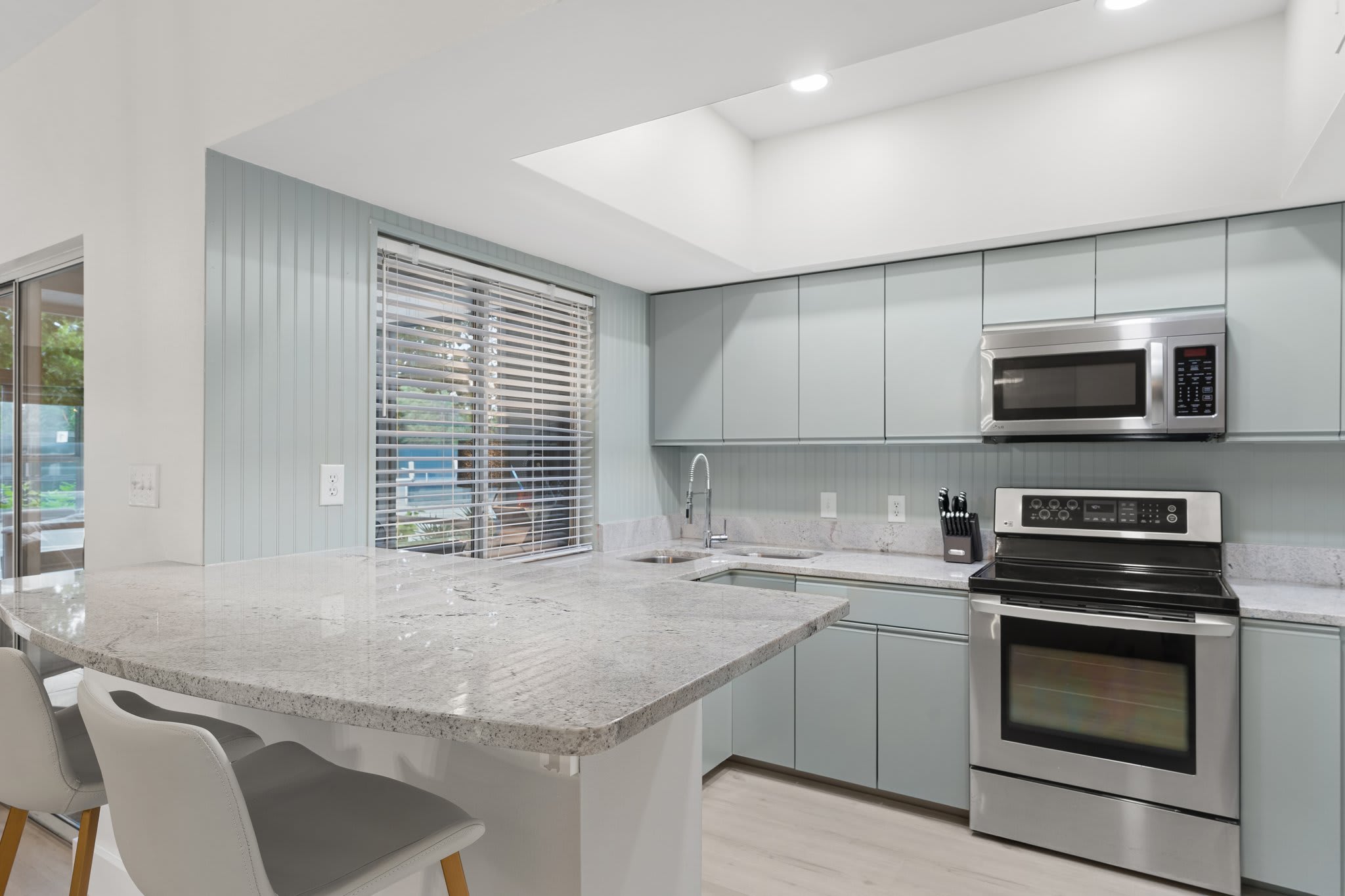 This modern kitchen shines with wood cabinetry, granite counters, and stainless-steel appliances.