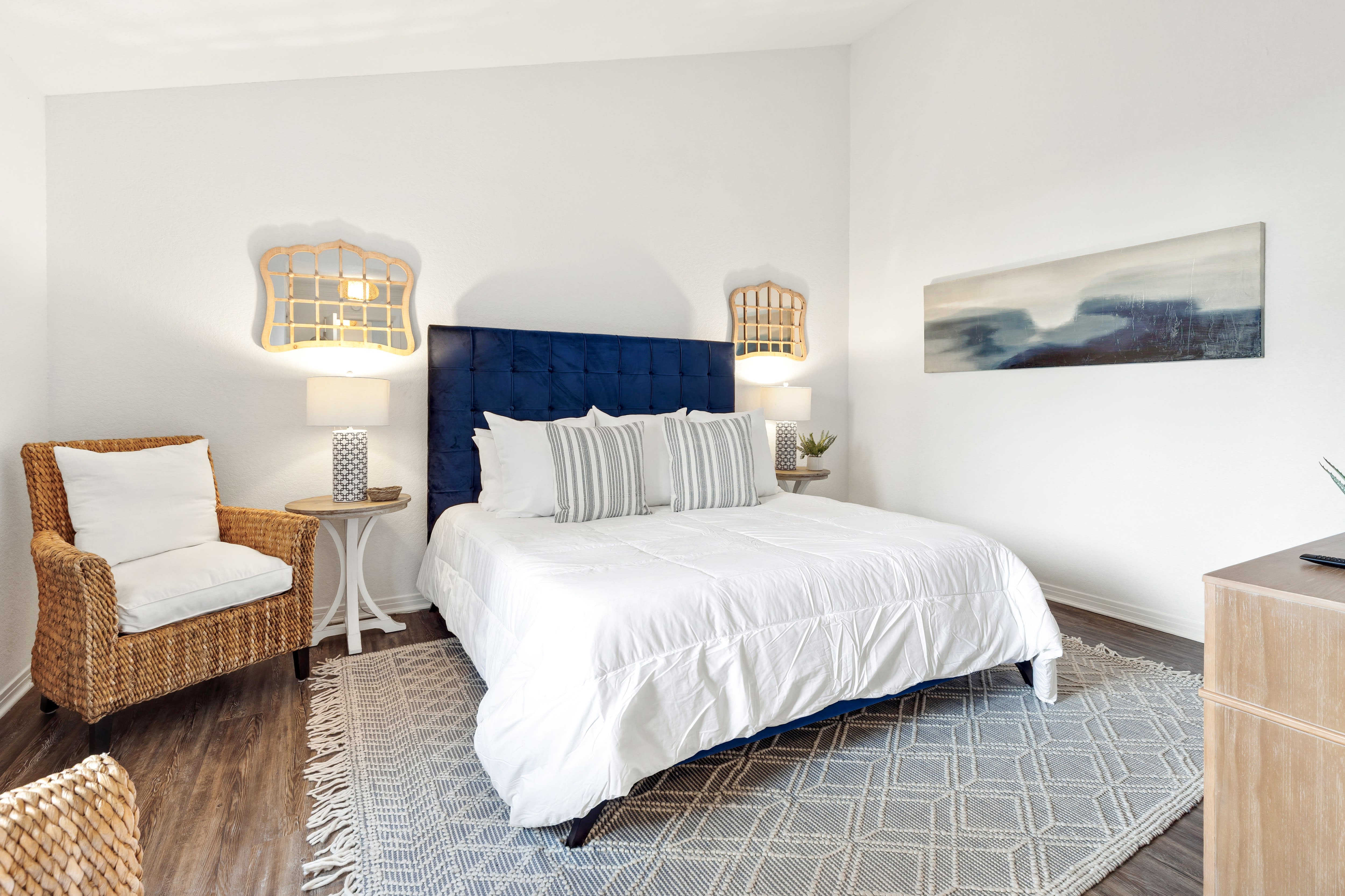 Your coastal-inspired bedroom features crisp linens, nautical pendant lights, and a cozy wicker reading chair perfect for unwinding.