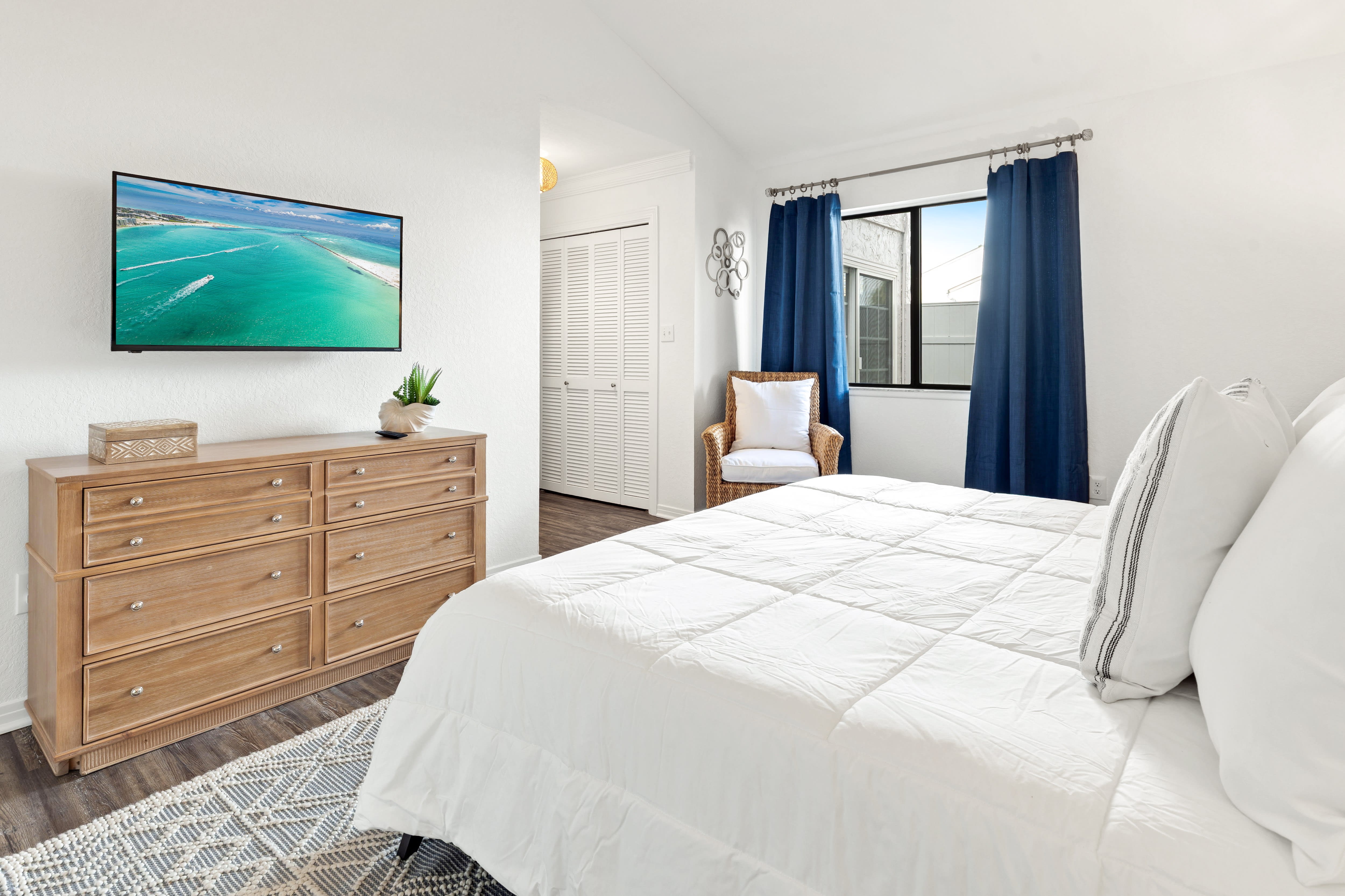 Unwind in your serene bedroom with plush white bedding, coastal TV entertainment, and a cozy reading nook by the window.