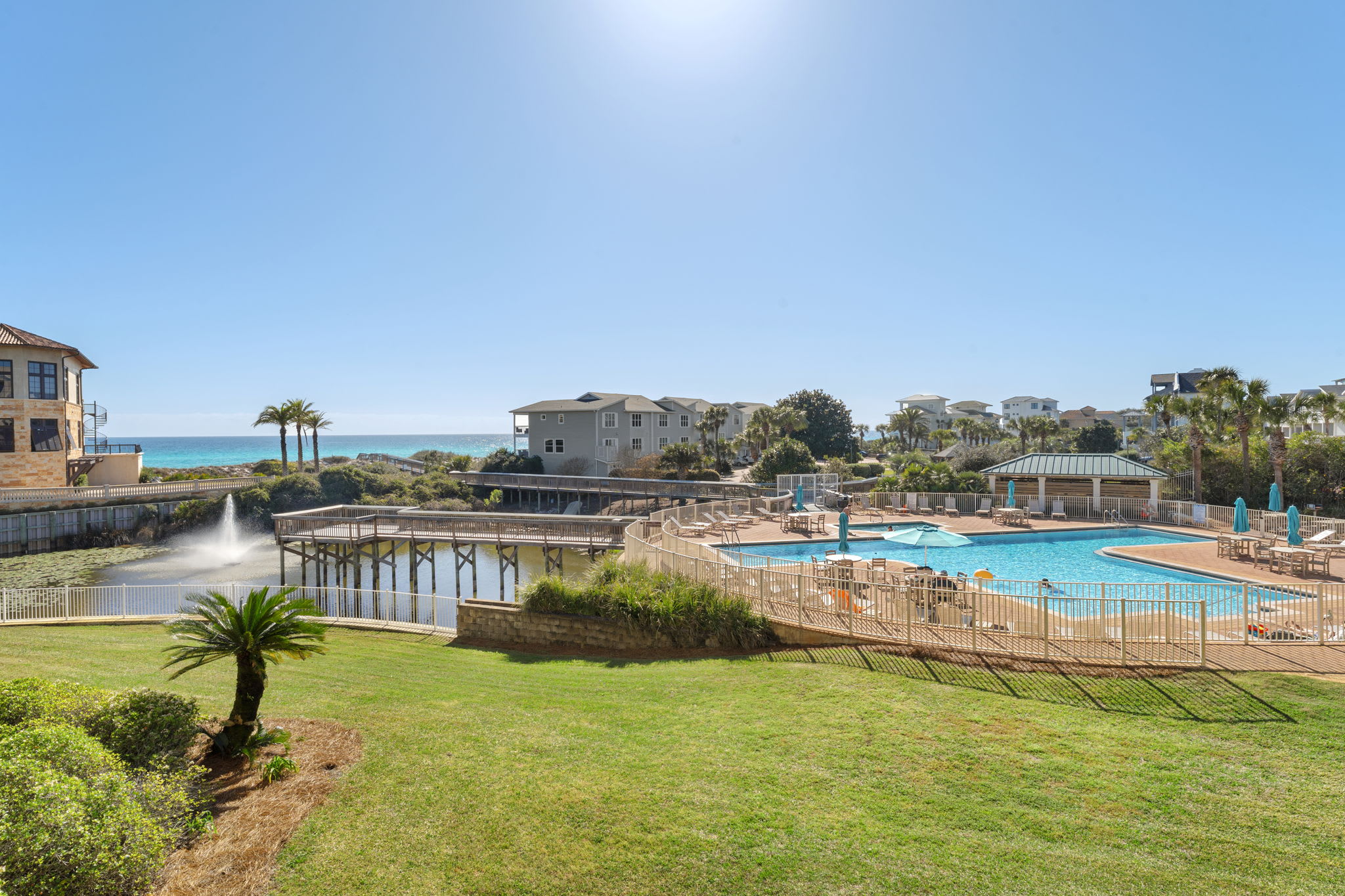 Stunning beachfront resort community with sparkling pool facilities and coastal views. Property buildings nestled among palm trees near pristine shoreline.