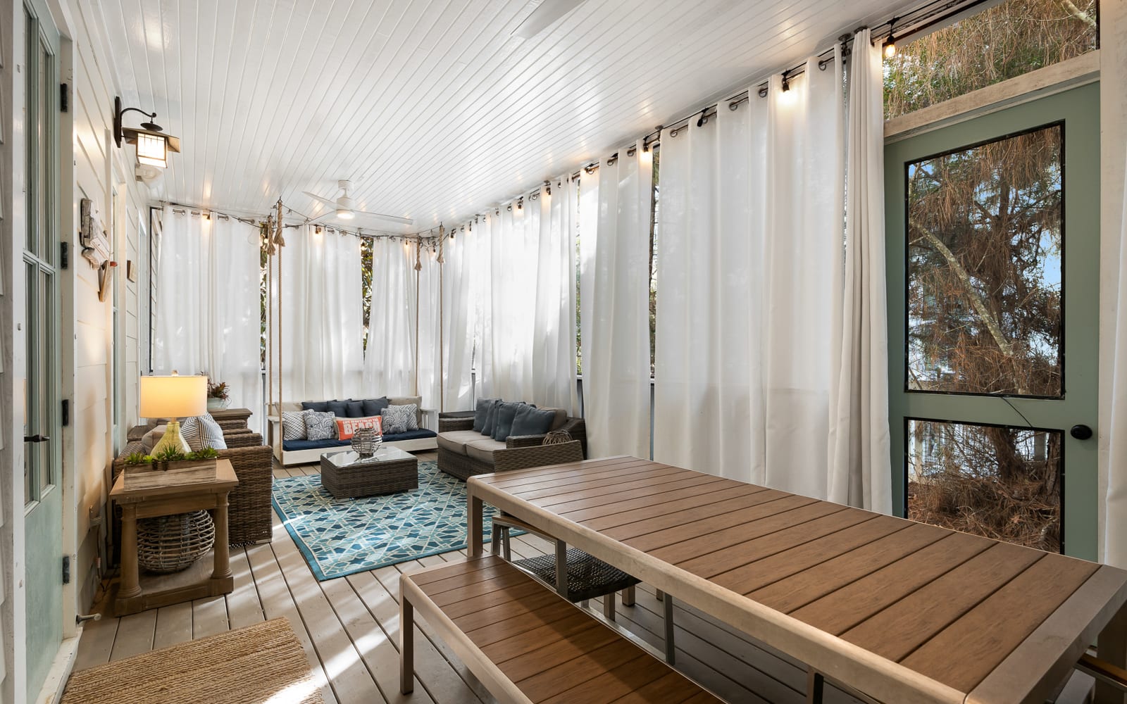 Your private screened porch invites you to unwind with plush seating, soft lighting, and peaceful garden views beyond flowing curtains.