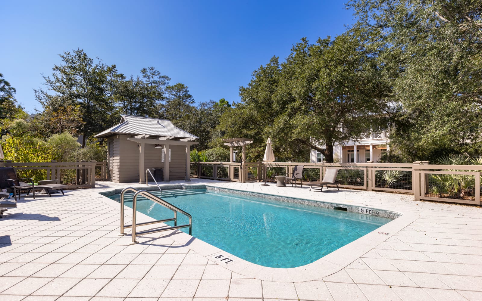 Oasis with crystal-clear pool waters surrounded by lush trees and comfortable lounging areas.