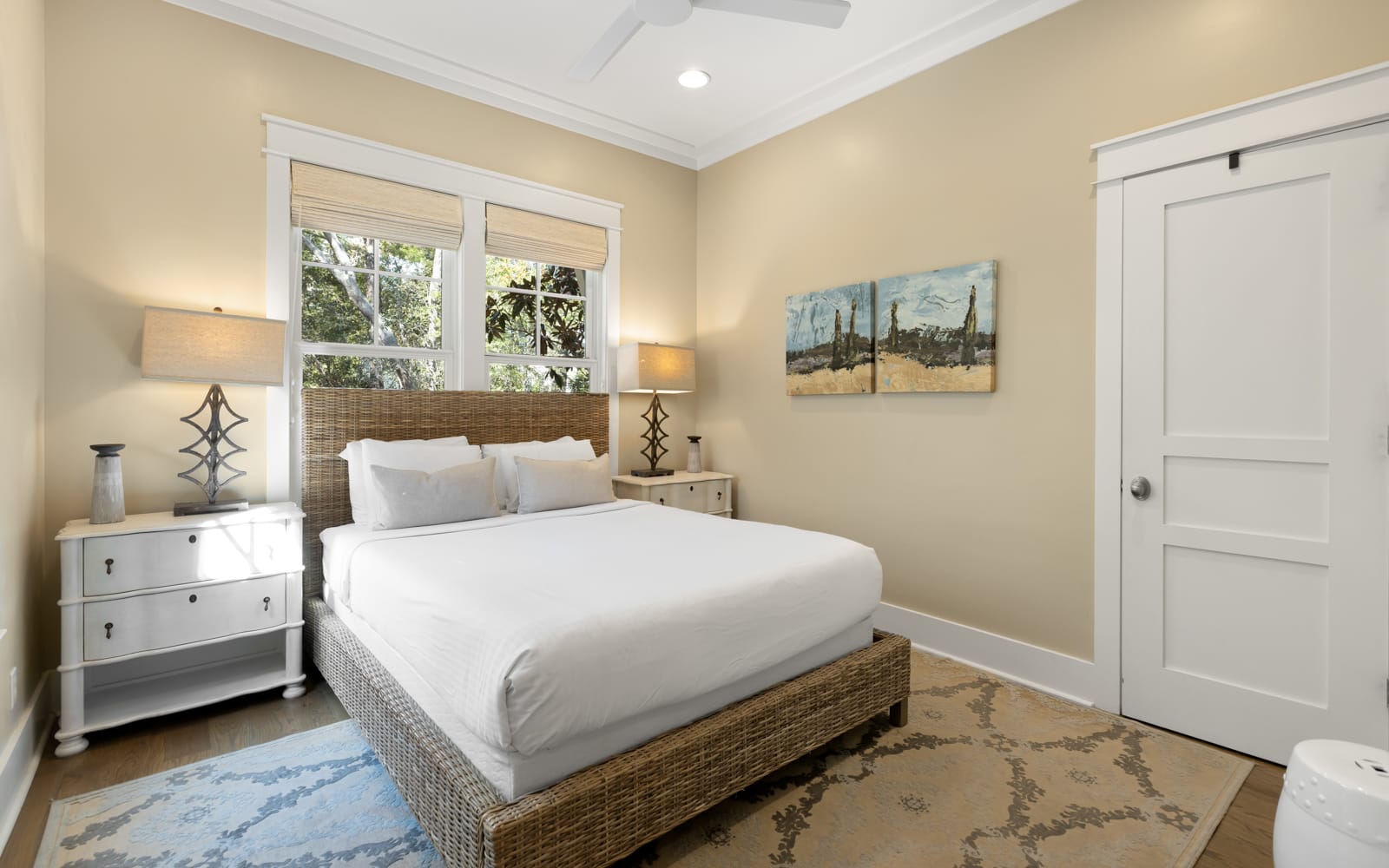 Slip into crisp white linens in your serene retreat, where warm natural light and coastal artwork create the perfect atmosphere for rest.