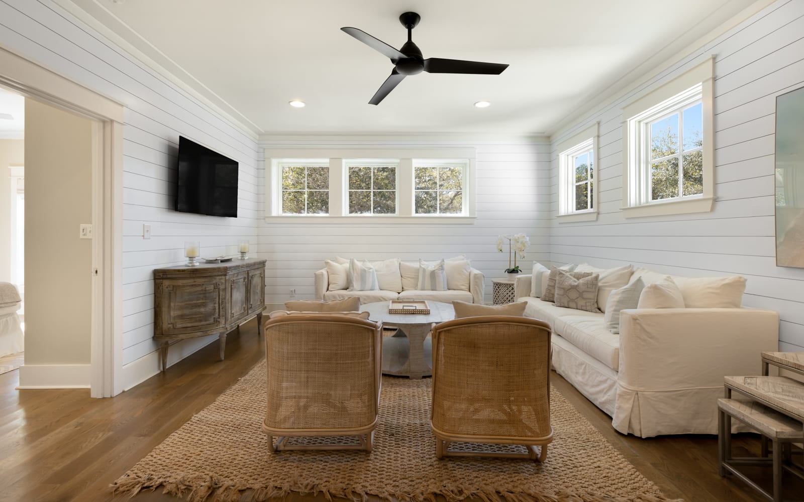 Sink into plush white sofas in this bright living room where shiplap walls and natural light create your perfect retreat space.