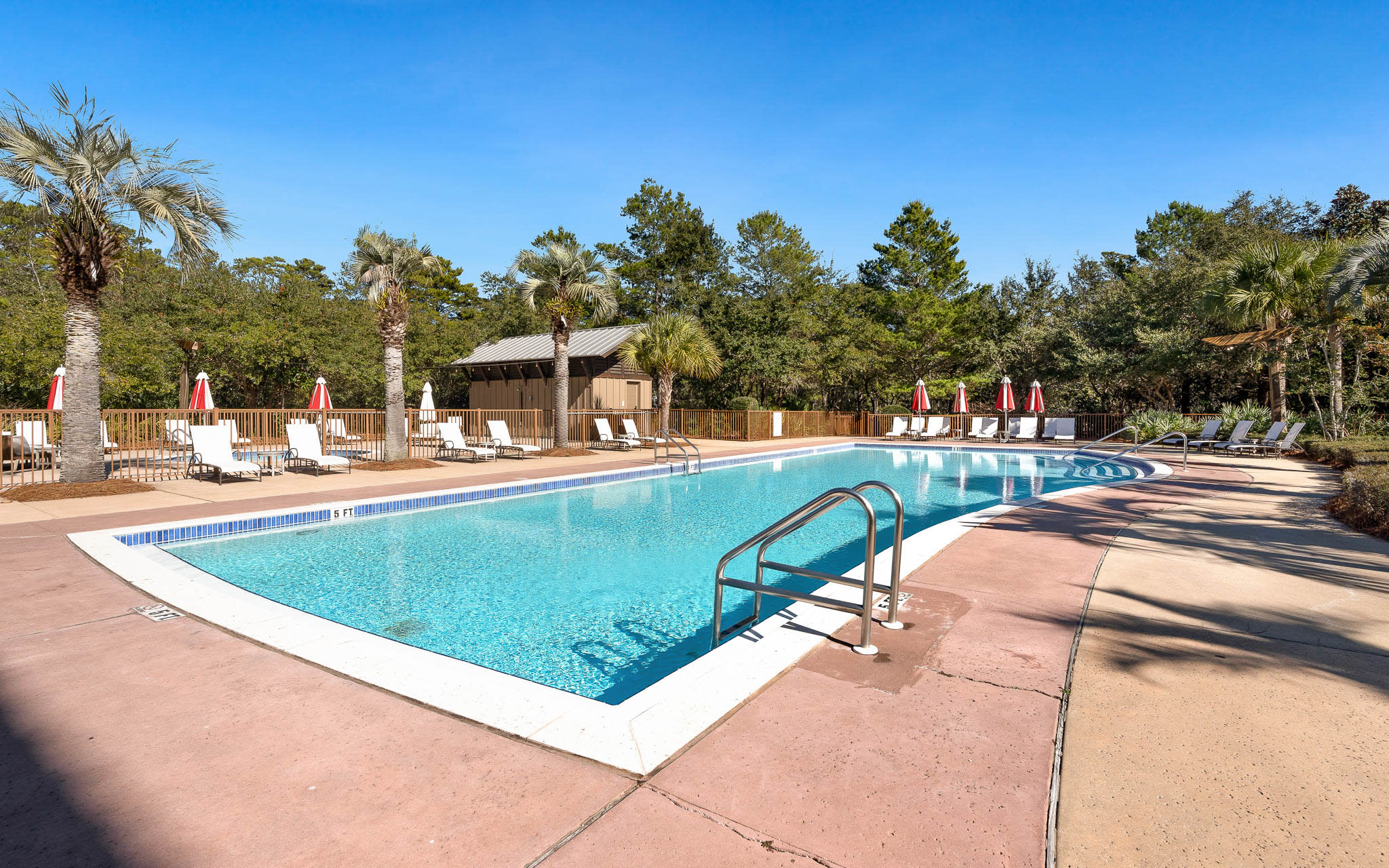 Sparkling pool surrounded by palm trees and lounge chairs where you can soak up the sun and unwind in paradise.