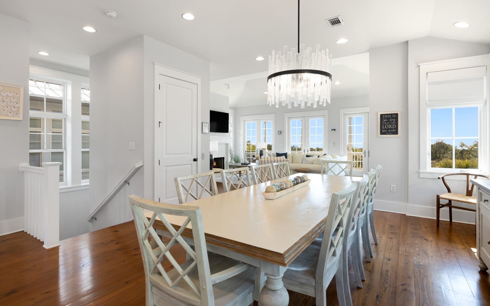 Gather around this elegant dining table where coastal charm meets sophisticated style, with crystal chandelier overhead creating perfect ambiance for memorable meals.
