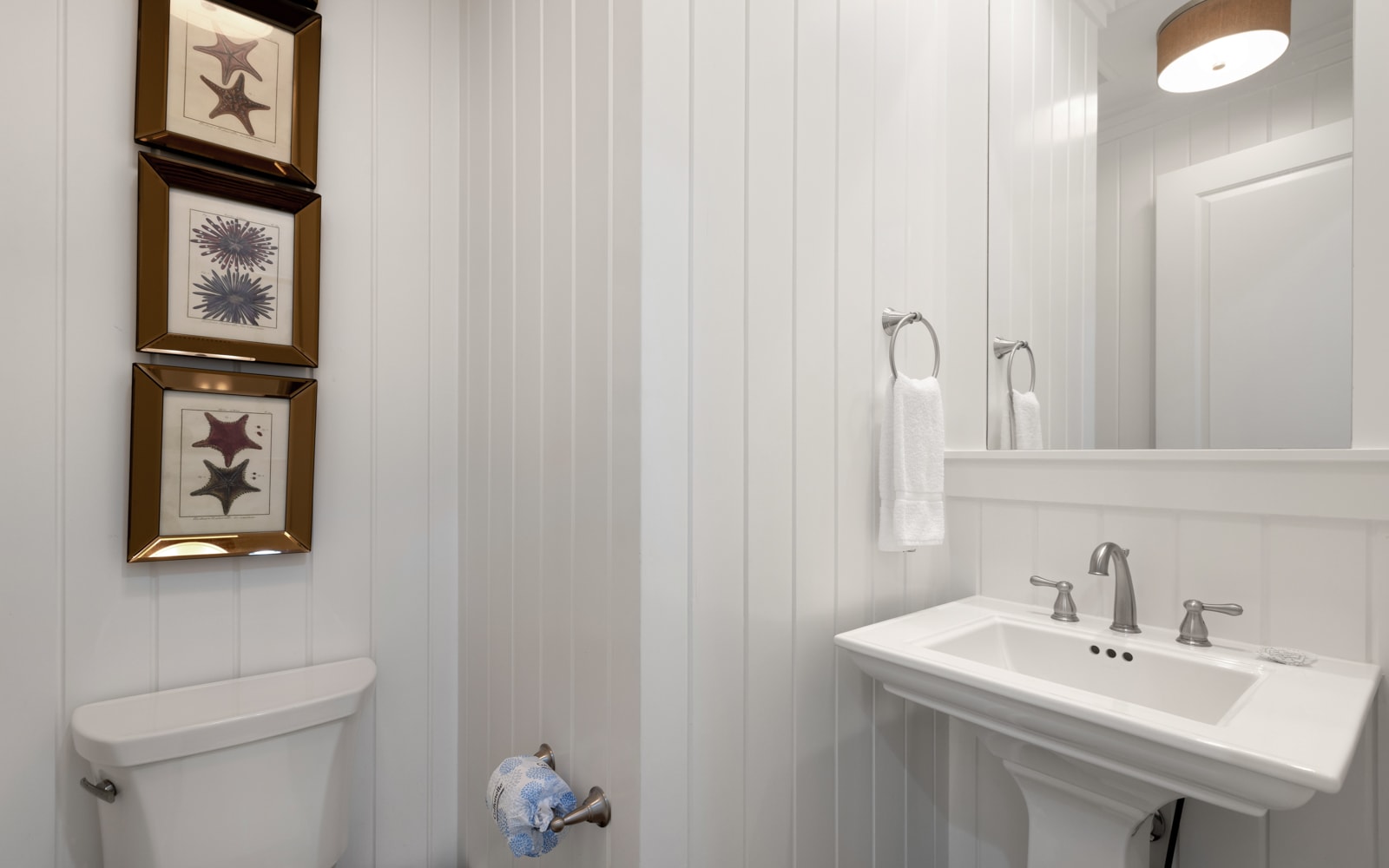 Step into your private coastal-themed bathroom with charming beadboard walls and nautical artwork that captures seaside serenity.