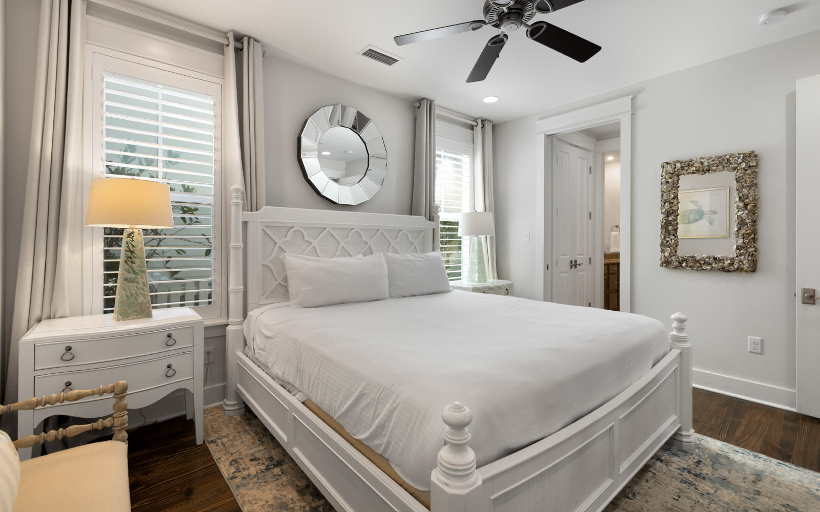 Drift off in your serene white bedroom with plush linens, coastal charm, and gentle ceiling fan keeping you cool.