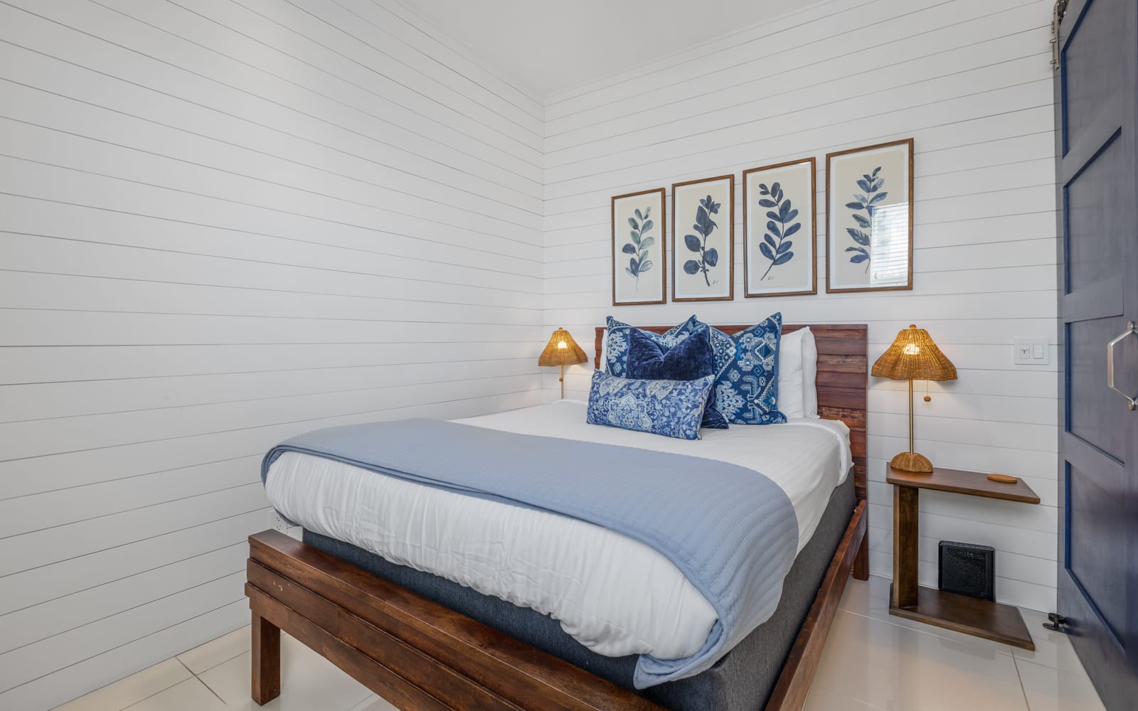 Drift off in your serene coastal-inspired bedroom, where crisp white shiplap meets ocean blues and warm wood tones for ultimate relaxation.