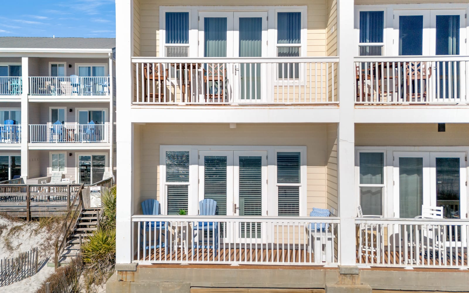 Gulf front property featuring multi-level balconies with coastal architecture and nearby vacation rental buildings.