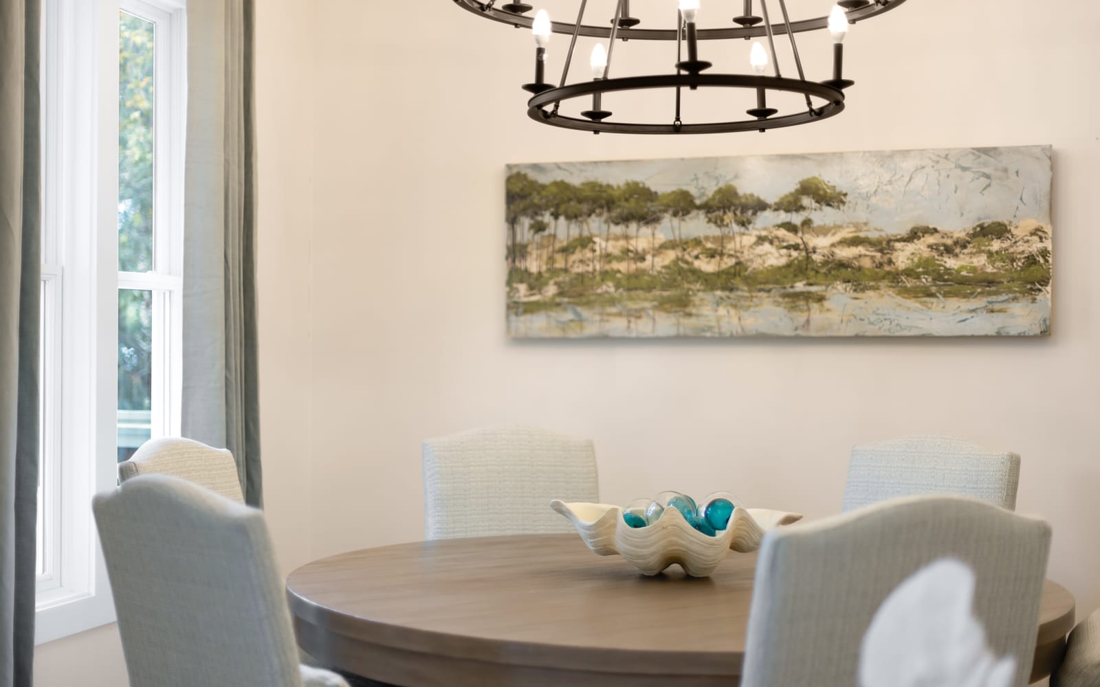 Your elegant dining space features a round table perfect for intimate meals, complemented by soft natural light.