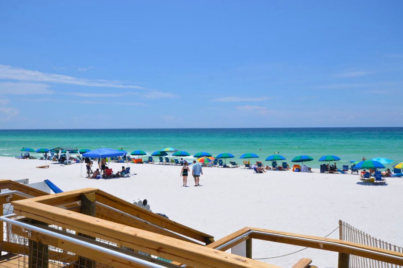 Spacious private beach with sugar-white sand, colorful umbrellas, and emerald Gulf waters—ideal for relaxing, swimming, and soaking up the laid-back coastal atmosphere.
