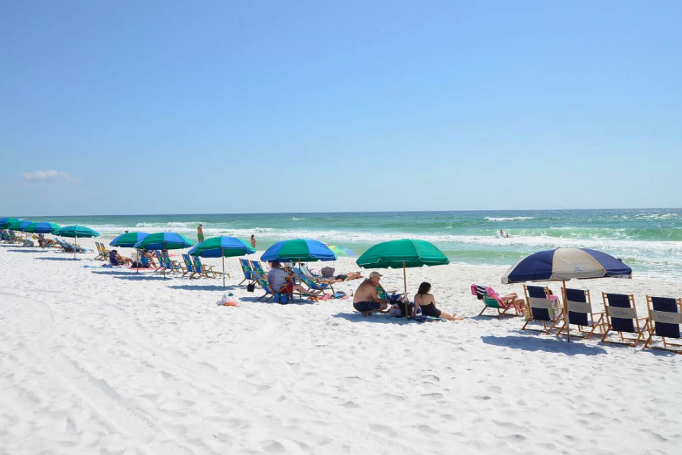Sun-soaked private beach with sugar-white sand, emerald Gulf waters, and colorful umbrellas creating the perfect setting for relaxing, swimming, and enjoying classic Emerald Coast beach days.