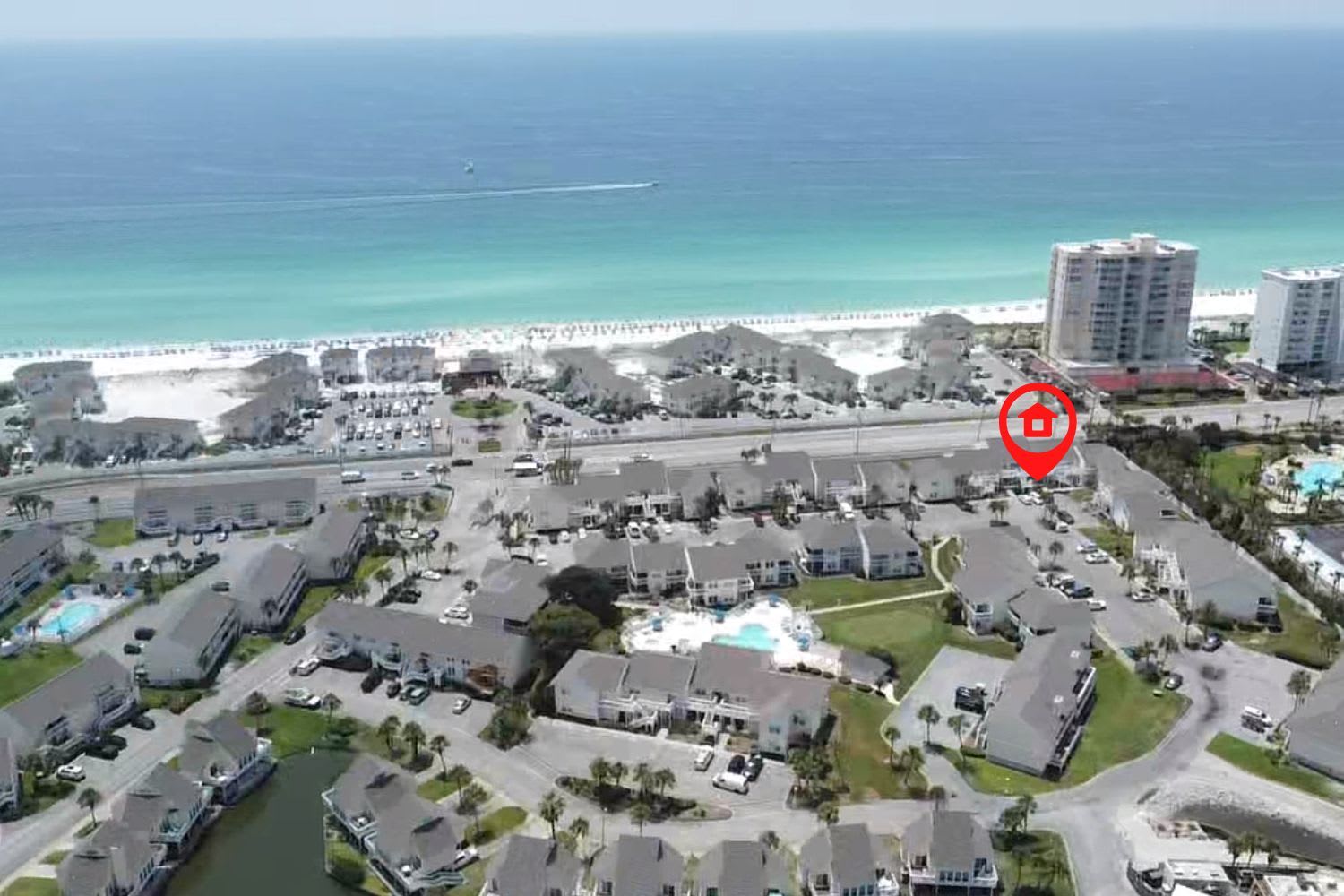 Aerial view of beachfront resort community with pristine white sand beach and emerald waters just steps away from the property.