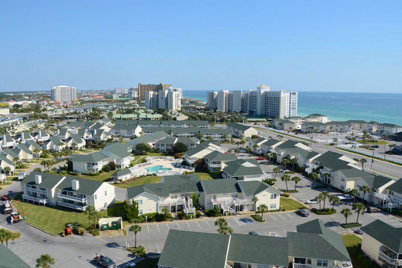 Aerial view of beachfront resort community with distinctive green rooftops and high-rise hotels along the pristine coastline.