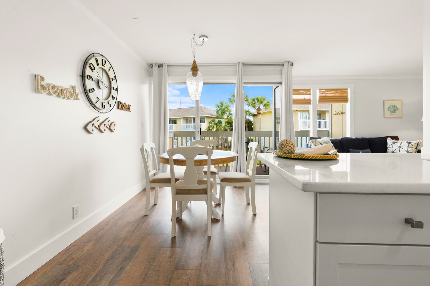 Your bright, open living space flows seamlessly from kitchen to dining, with palm trees swaying beyond your private balcony doors.