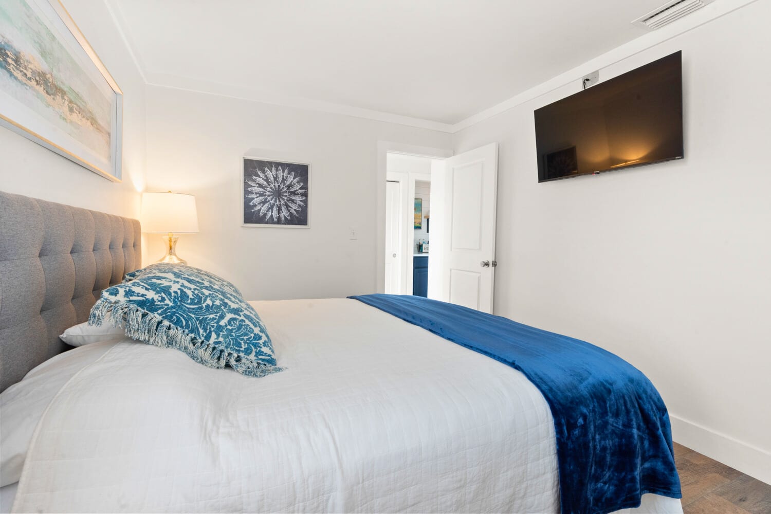 Your serene bedroom awaits with a plush tufted headboard, crisp linens, and soothing blue accents. Unwind while watching your favorite shows on the wall-mounted TV.