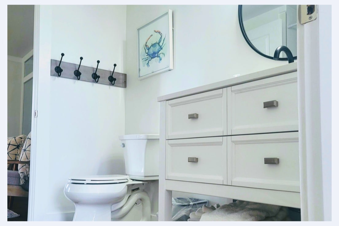 Your bright bathroom features coastal charm with a vanity offering ample storage and convenient wall hooks for your belongings.