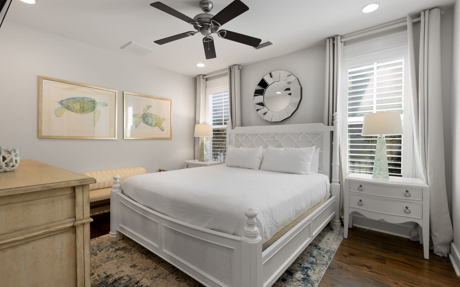Rest peacefully in this elegant bedroom featuring a plush queen bed, calming sea turtle artwork, and gentle ceiling fan for your comfort.