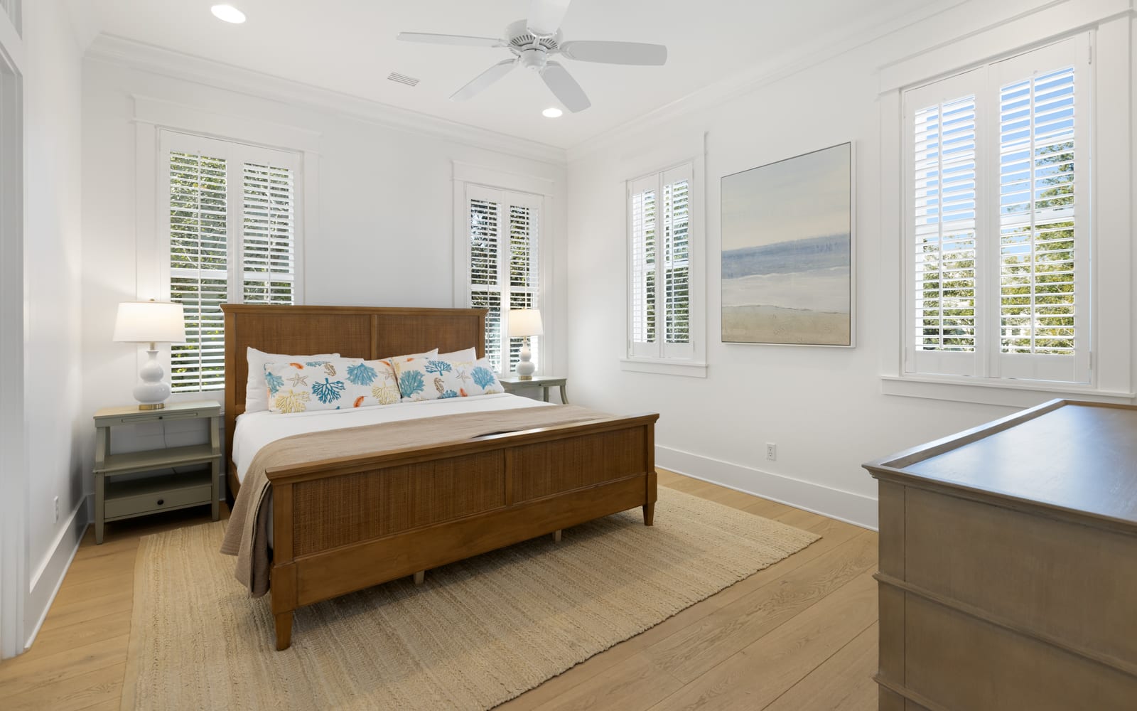 Your bright bedroom features coastal charm with crisp white linens, elegant wood furnishings, and plantation shutters filtering gentle natural light.