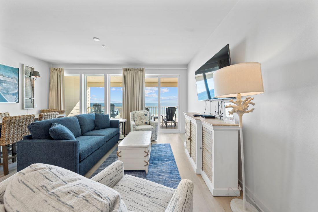 Your coastal living room features plush seating and oceanfront balcony access for perfect relaxation.