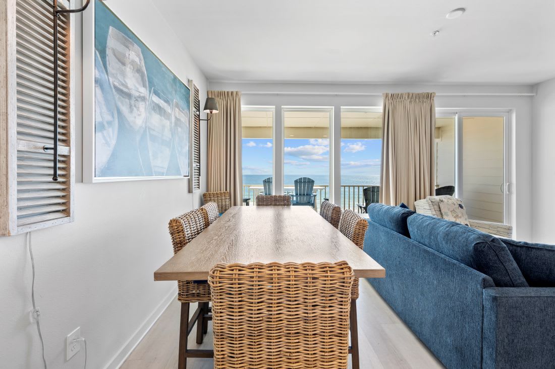 Gather around the natural wood dining table while gazing at stunning ocean views through floor-to-ceiling windows.