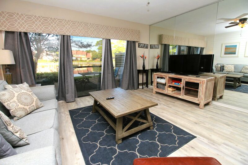 Spacious living room with large windows that let in natural light and flat screen TV