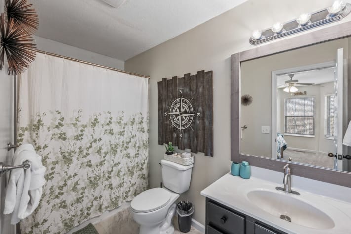 Modern bathroom with a shower/tub combo, large vanity mirror, stylish décor, and… Pigeon Forge, Tennessee Cabin Rental - Gallery Image #15