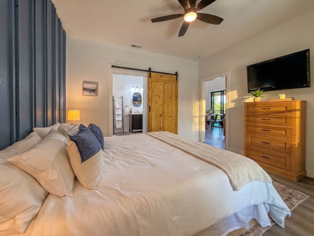 Primary suite with smart TV and sliding barn door — the private hot tub is just… Douglas Lake, Tennessee Cabin Rental - Gallery Image #29