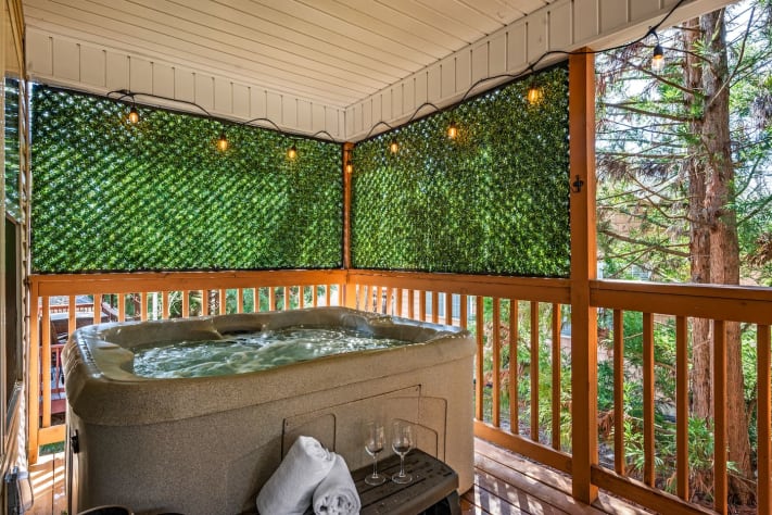 This inviting covered deck features a private hot tub surrounded by lush greenery… Pigeon Forge, Tennessee Cabin Rental - Gallery Image #25
